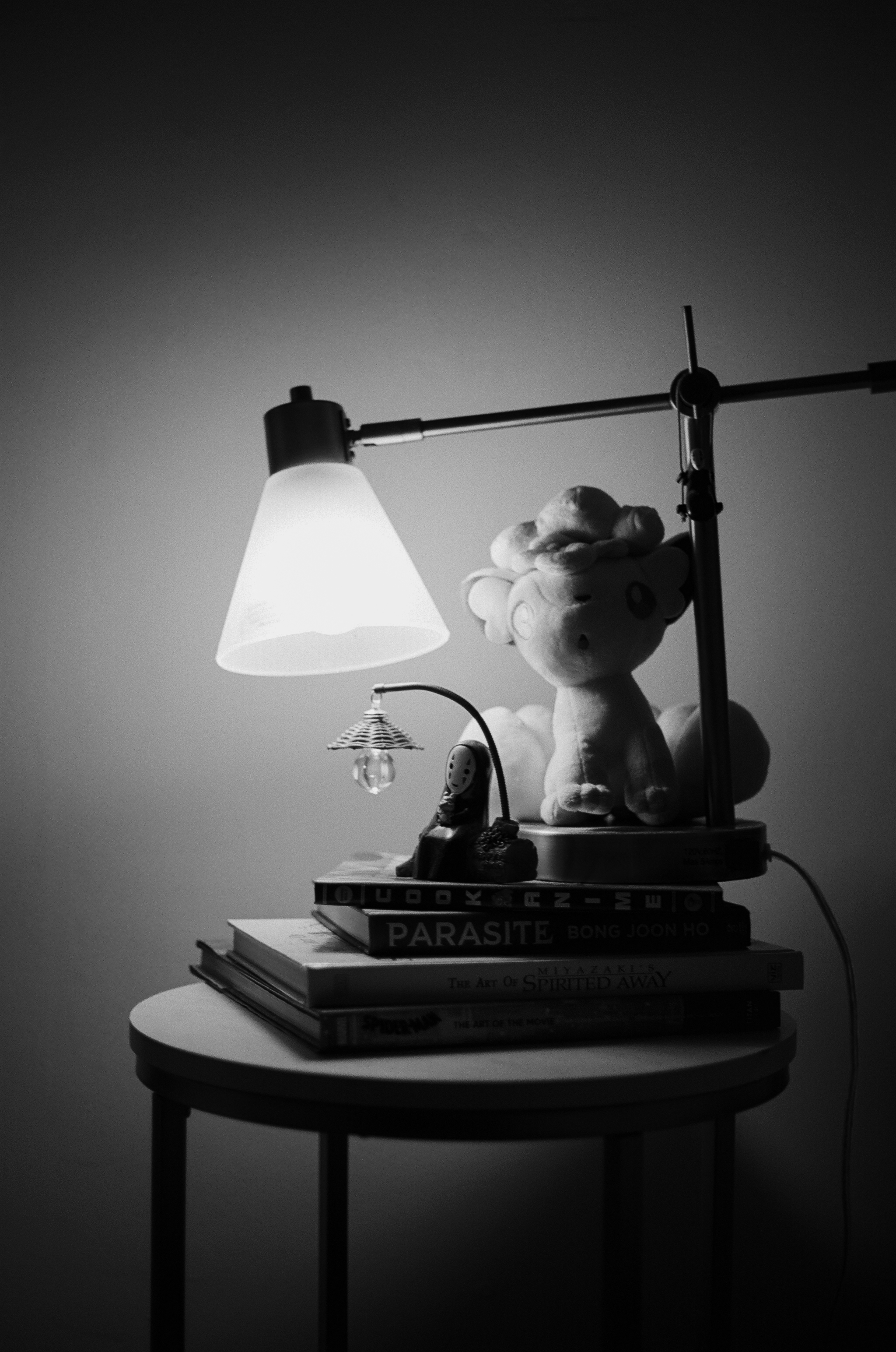 a black and white photo of books and a lamp on a table