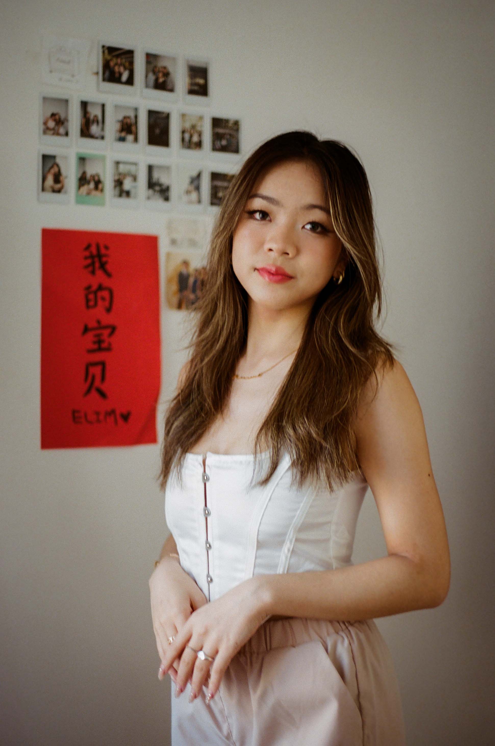an asian woman posing in her bedroom next to colorful artwork
