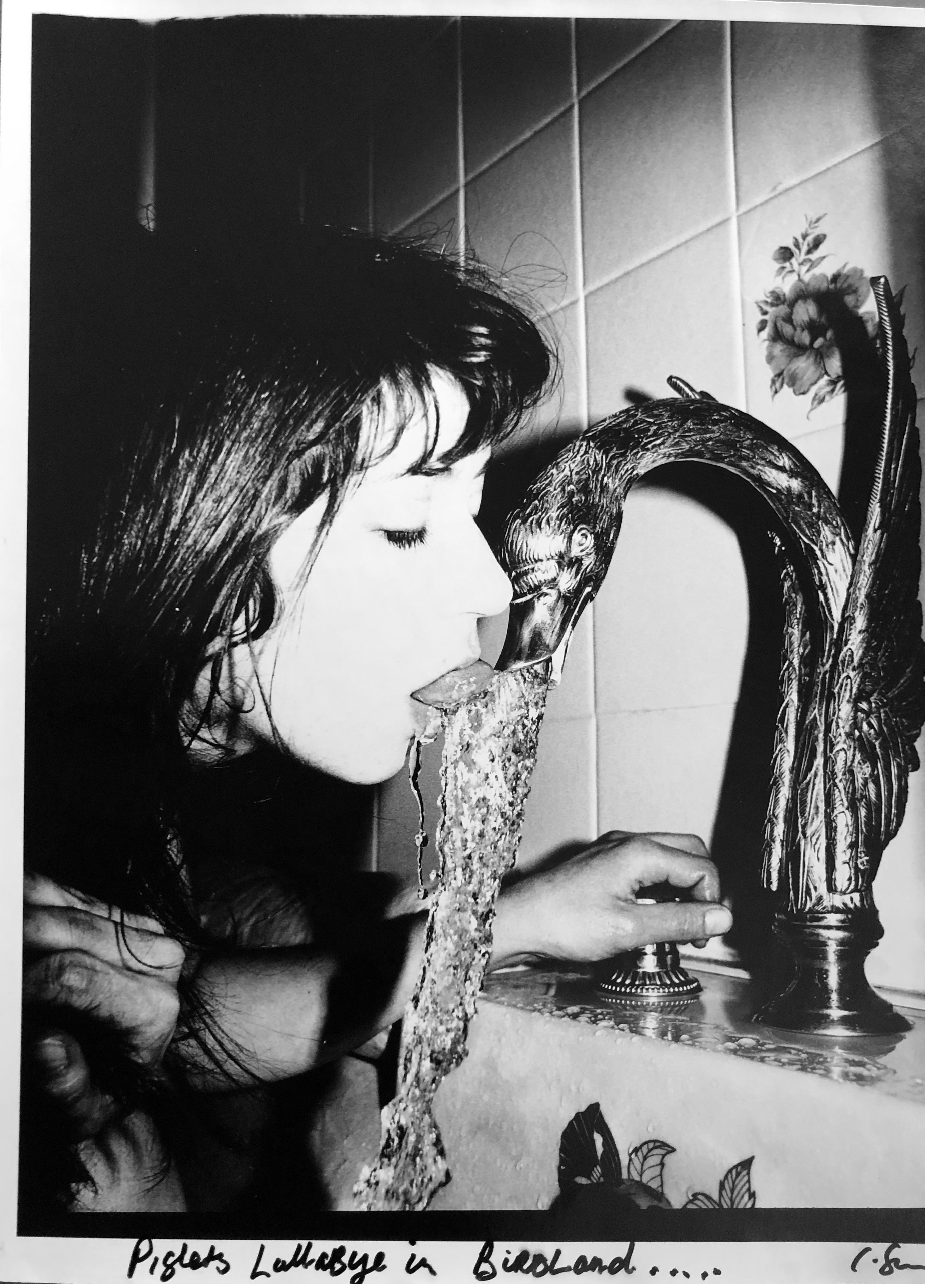 black-and-white image of a woman drinking from the tap