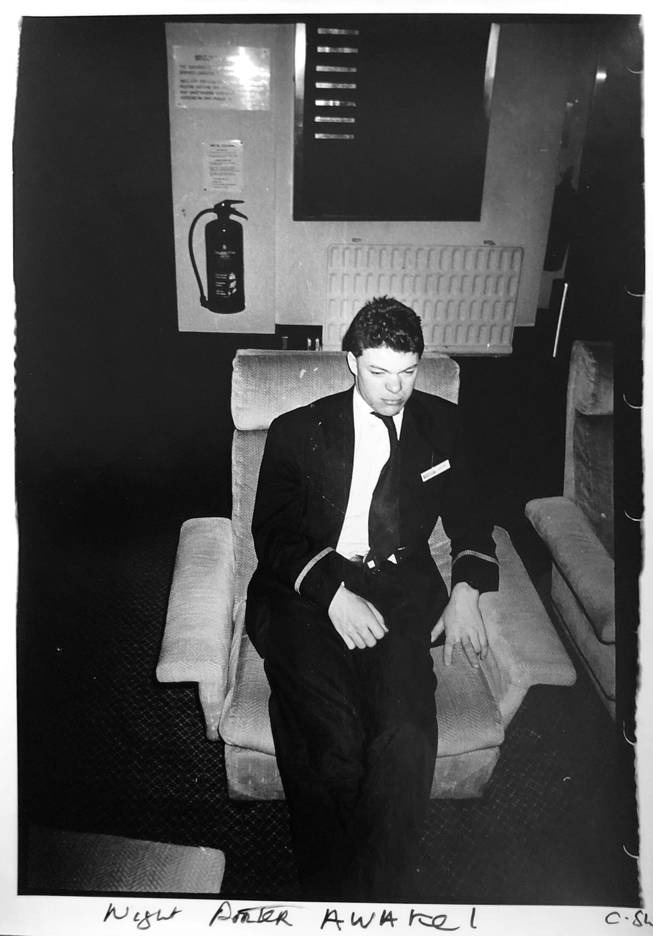 black-and-white image of a porter sitting in a hotel armchair