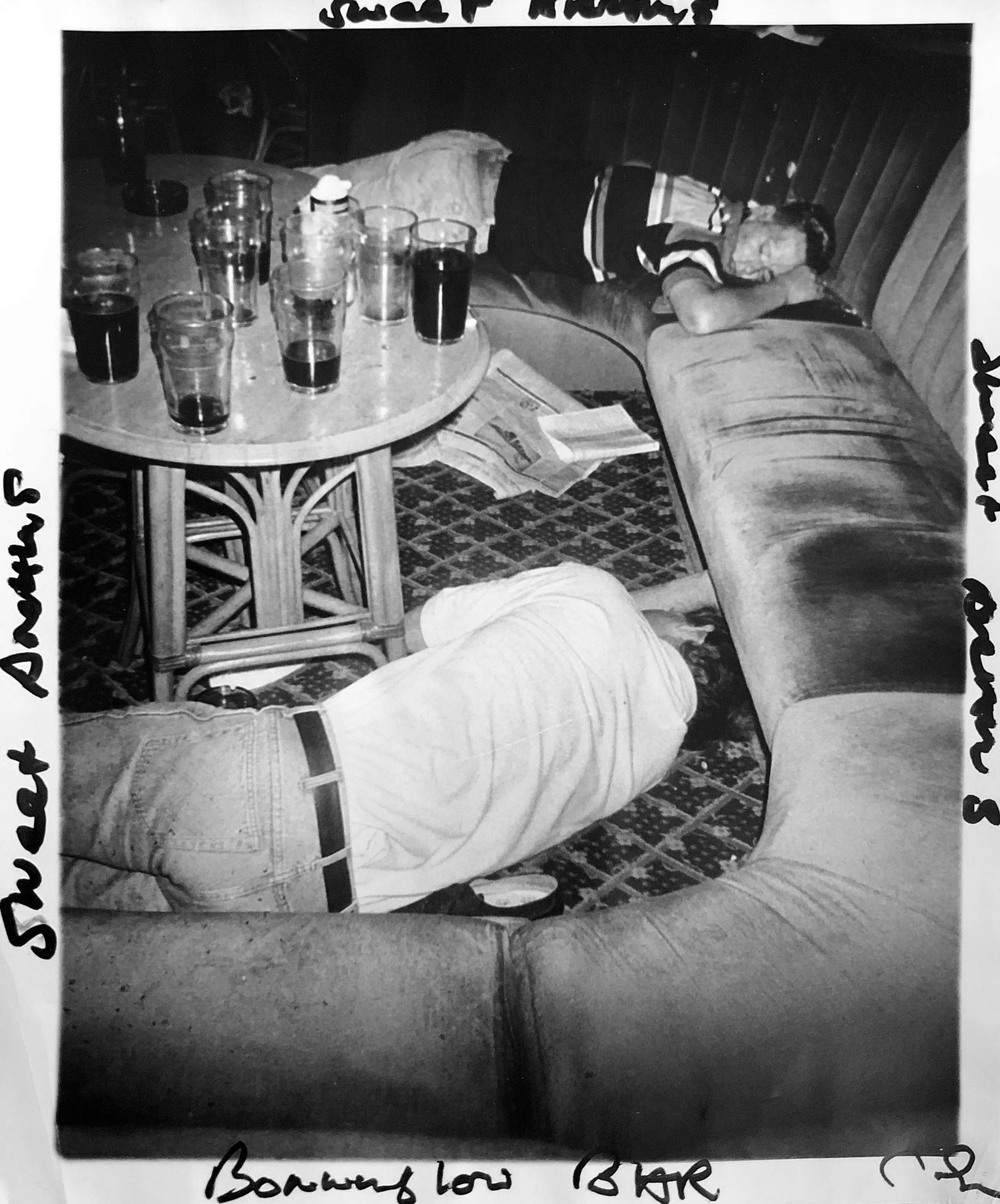black-and-white image of two men asleep at a hotel bar