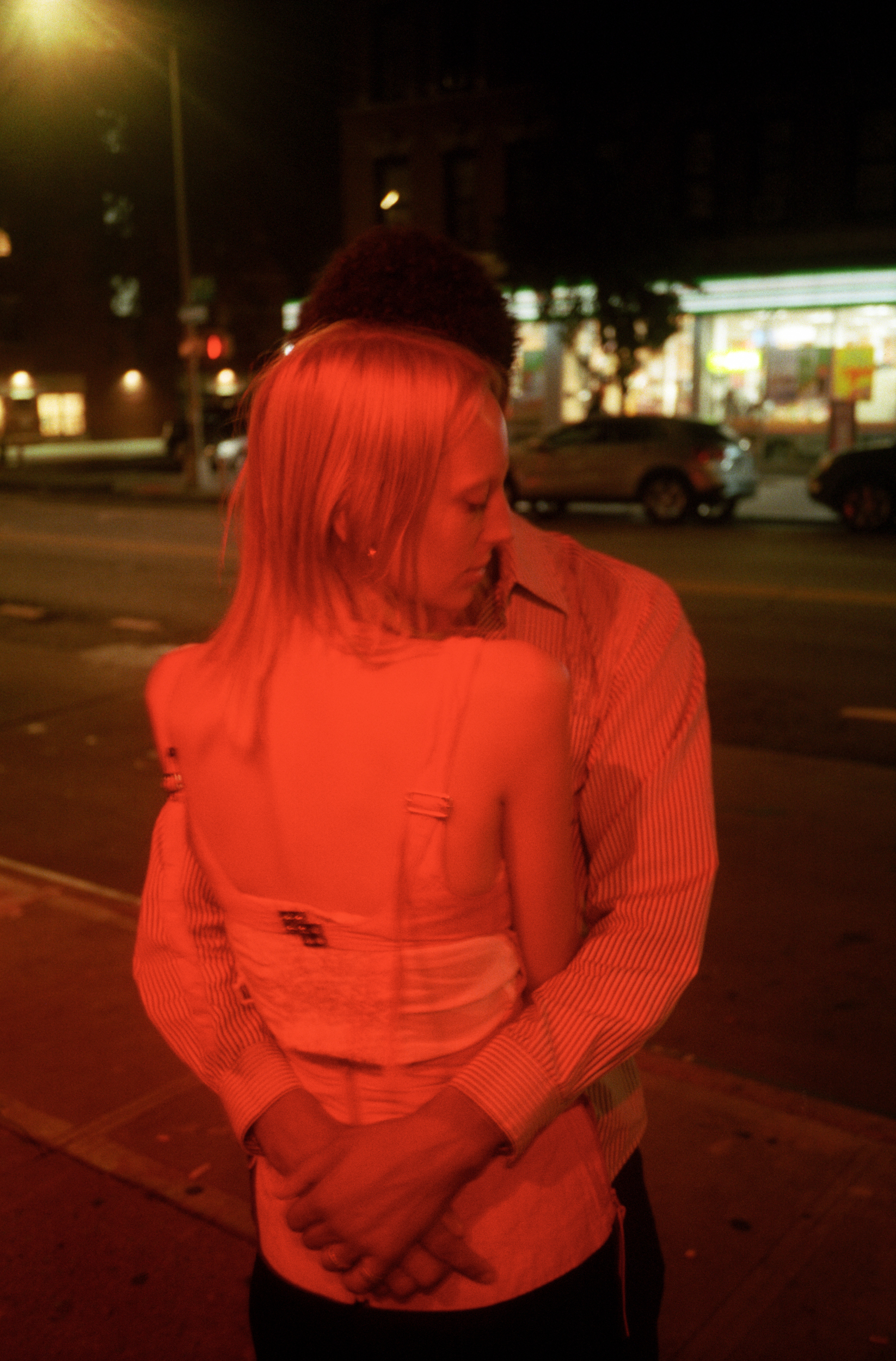 a couple embrace under red light in a NYC street 