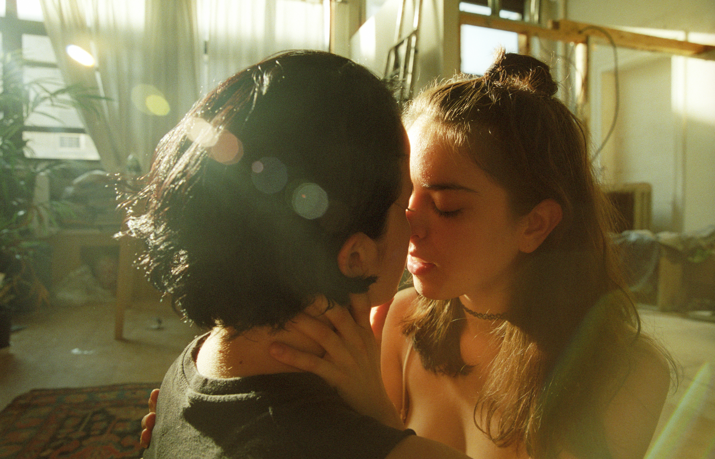 two people kiss in the sunlight of their apartment