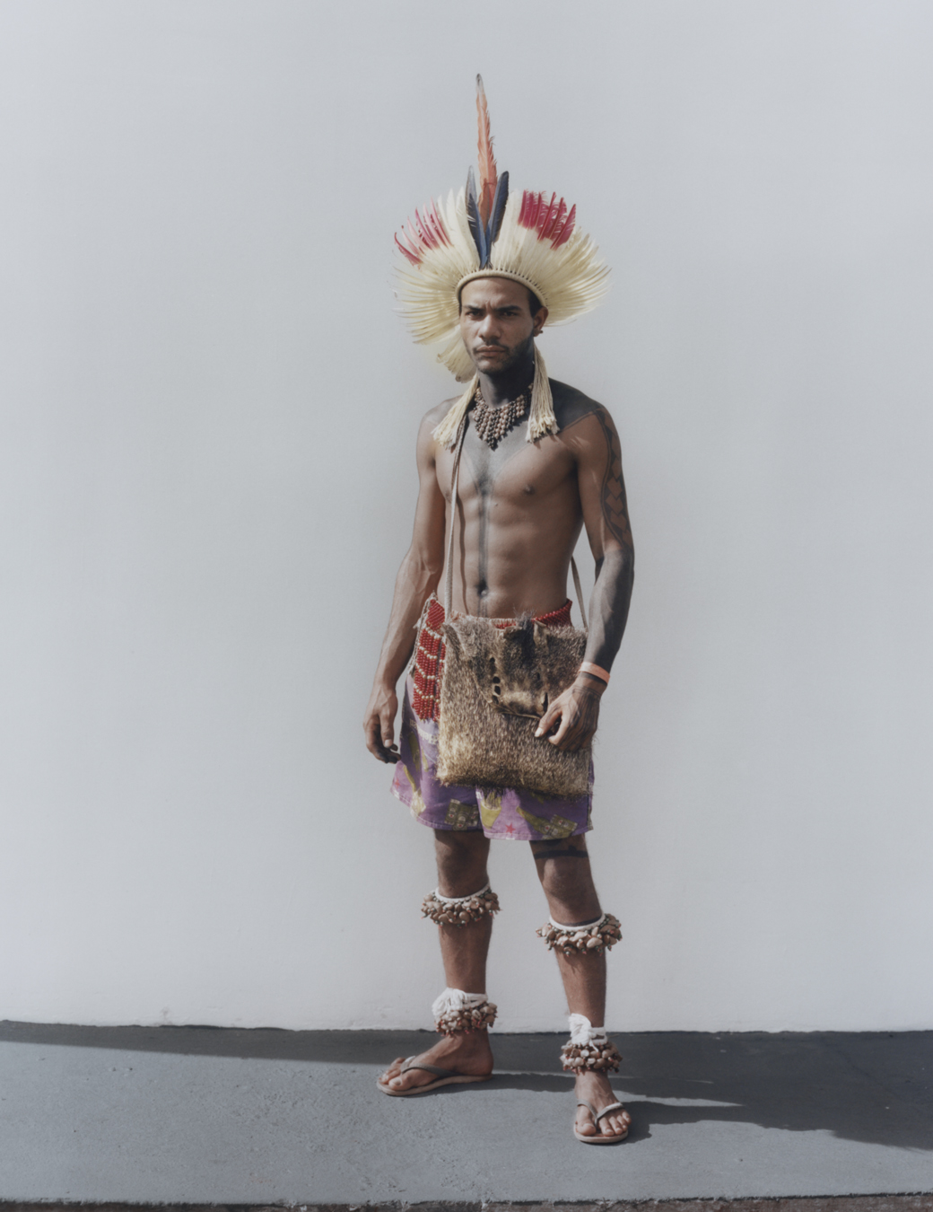 protester wearing traditional indigenous clothing standing against a wall