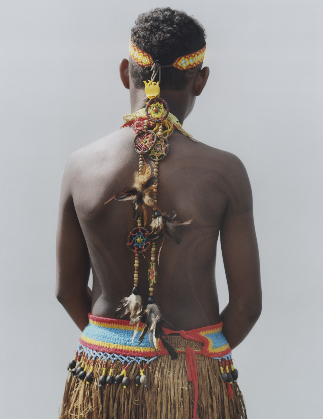 back of protester wearing traditional indigenous clothing standing against a wall
