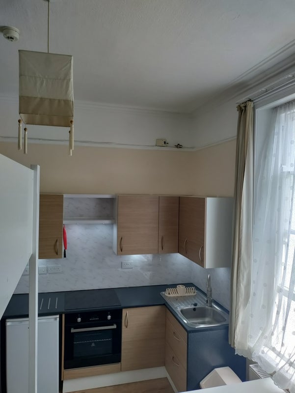 Tiny kitchenette in a one-bed bedsit in Crouch End with the staircase cut into a wardrobe