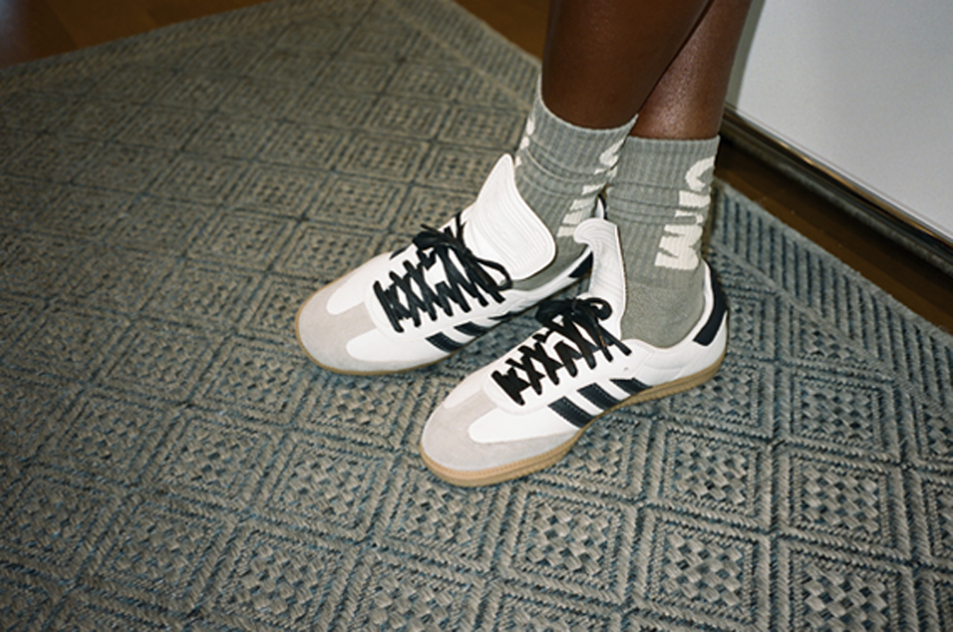 Primer plano de las zapatillas Adidas blancas y los calcetines grises de Pharrell Williams. 