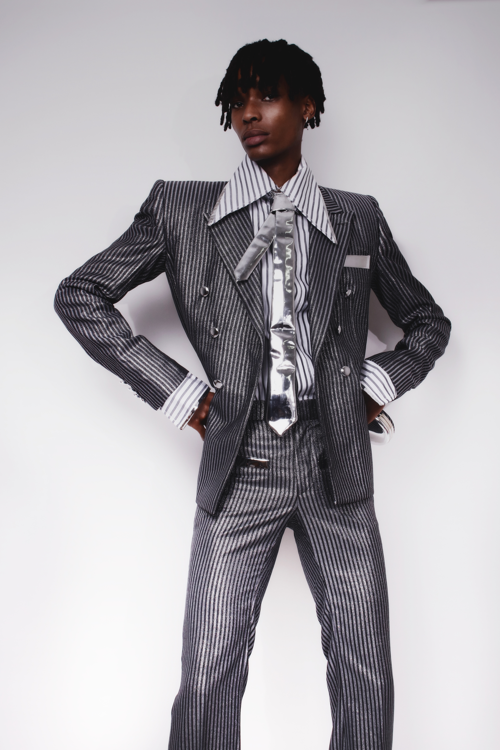 Model in striped silver suit, oversized shirt and silver tie in the pages of INCROWD magazine