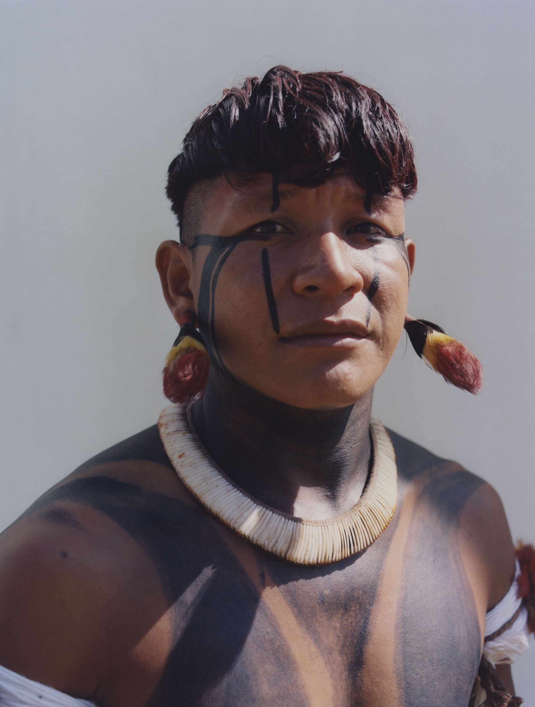 close up of protester wearing traditional indigenous clothing standing against a wall