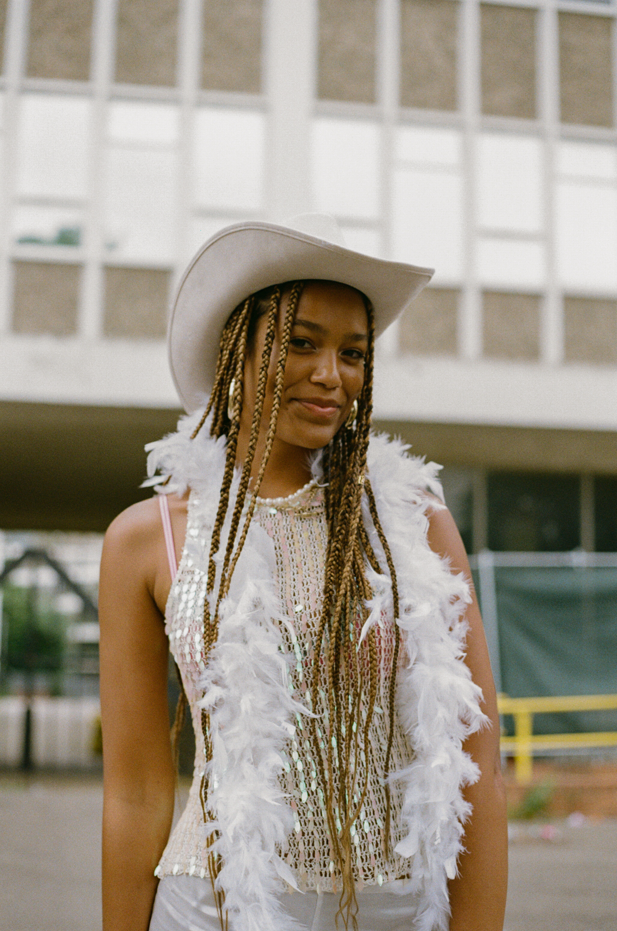 a harry styles fan wearing a white feather boa and a white cowboy hat