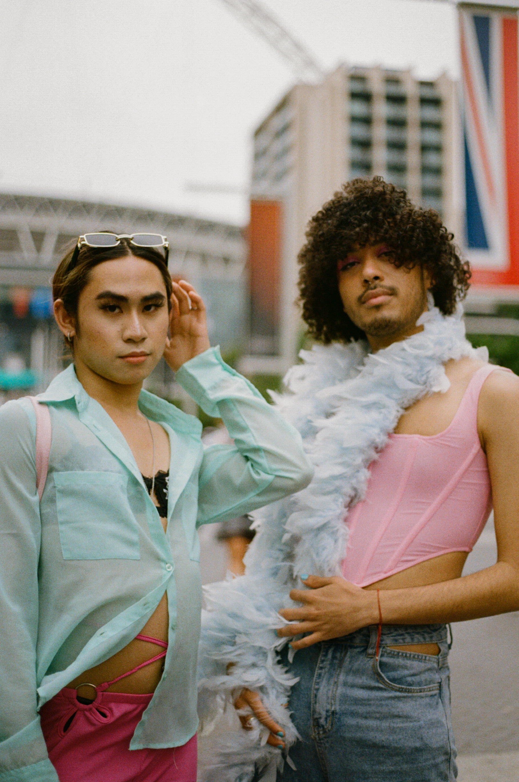 two harry styles fans in sheer shirts, pink corsets and feather boas