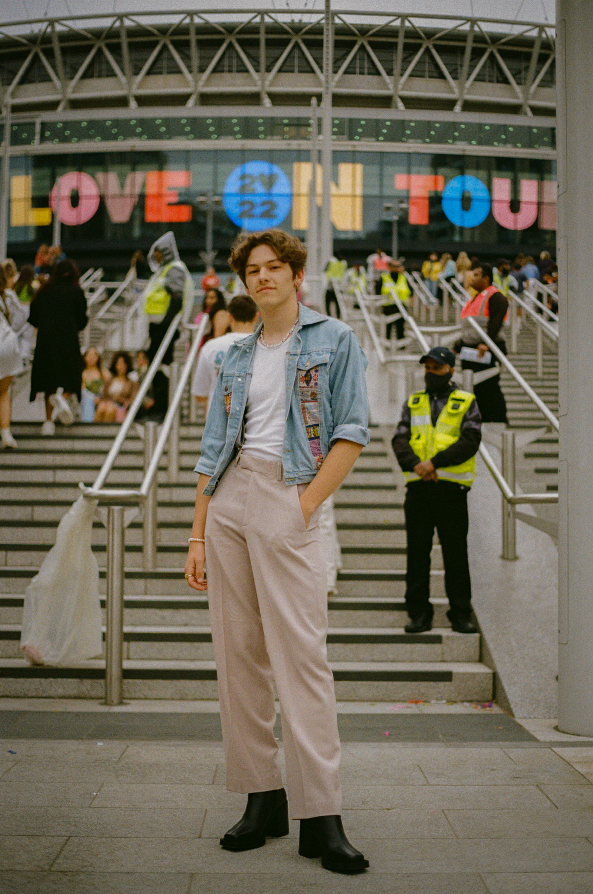 a harry styles fan in slacks, a denim jacket and a necklace