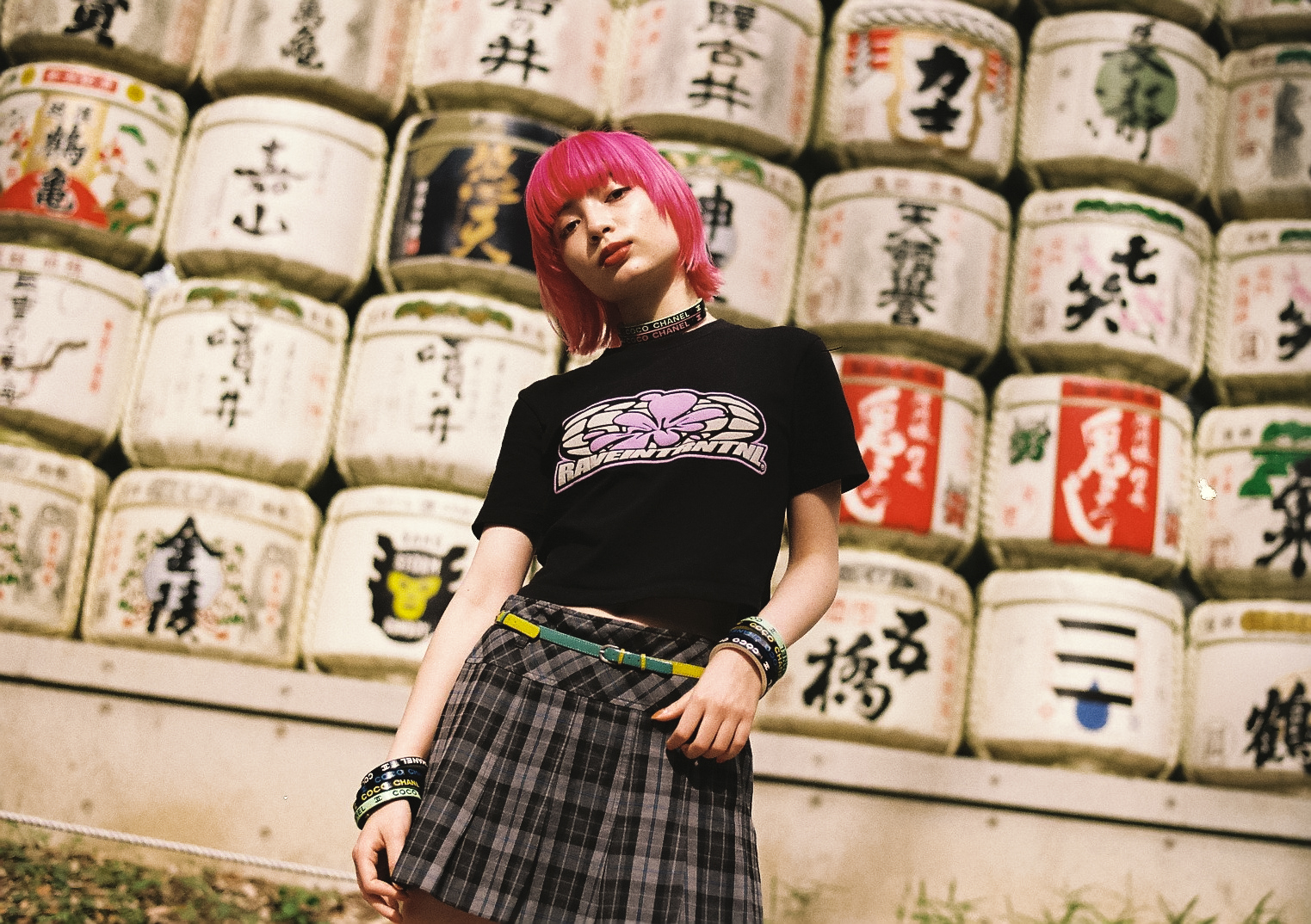 pink-haired manon wearing a school skirt in front of a wall of sake barrels in yoyogi park