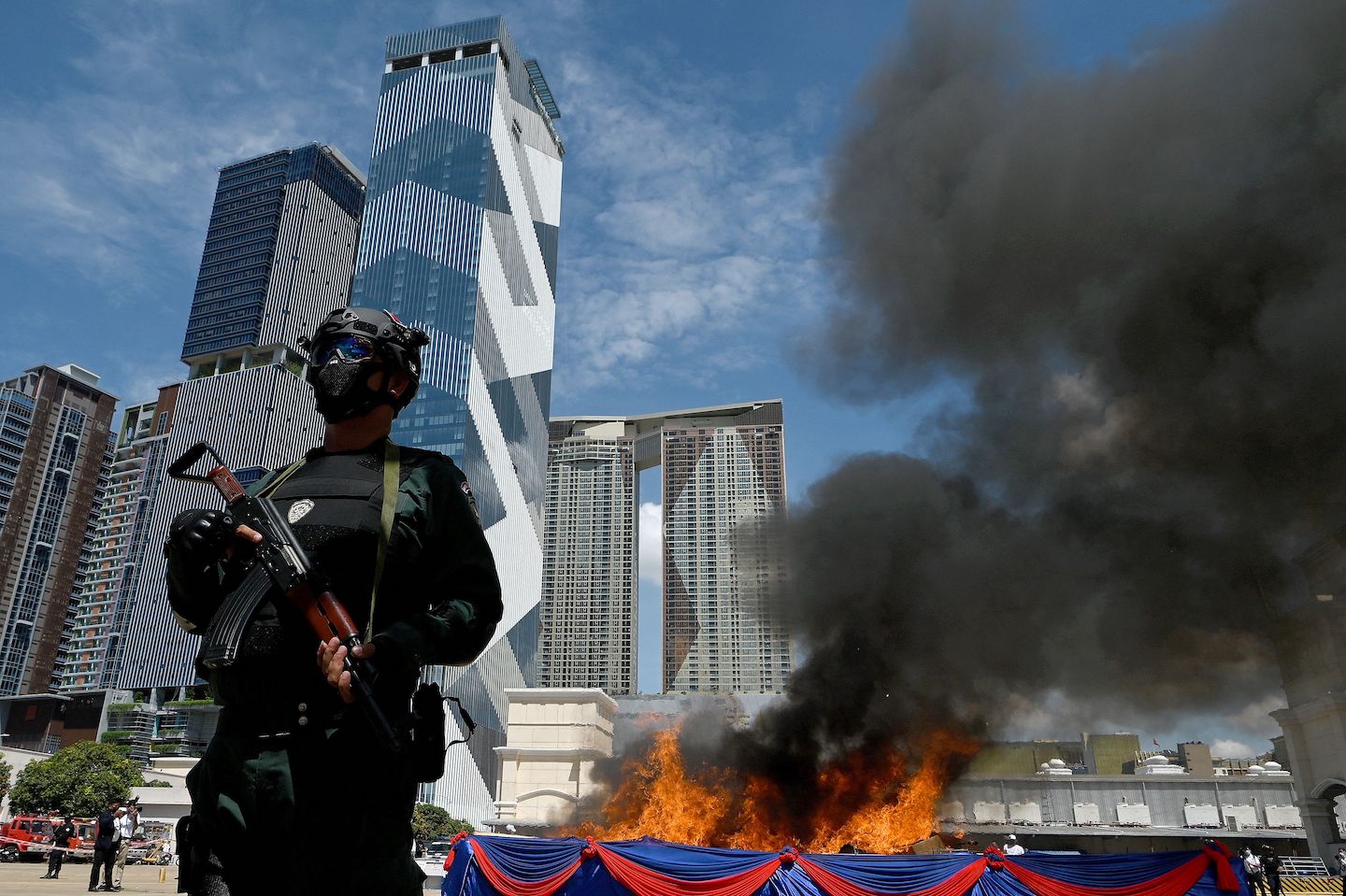Polisi Kamboja berjaga di depan kobaran api yang melalap tumpukan narkoba. Foto oleh Tang Chhin Sothy/AFP via Getty Images