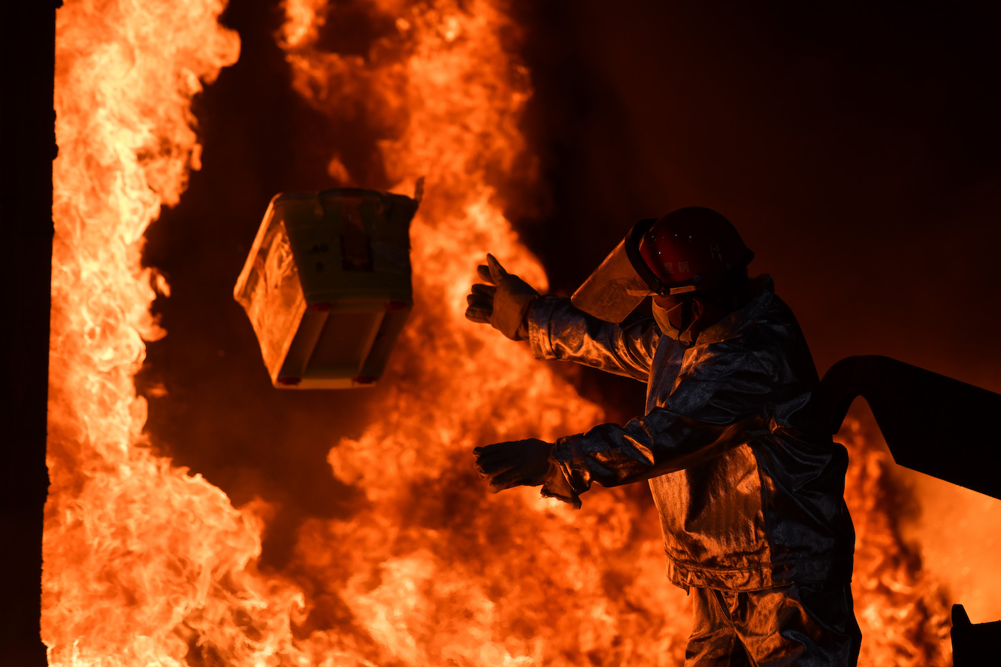 Seorang petugas melempar paket narkoba ke tungku pembakaran milik sebuah pabrik baja di Kunming, Provinsi Yunnan, Tiongkok. Foto oleh Liu Ranyang/China News Service via Getty Images