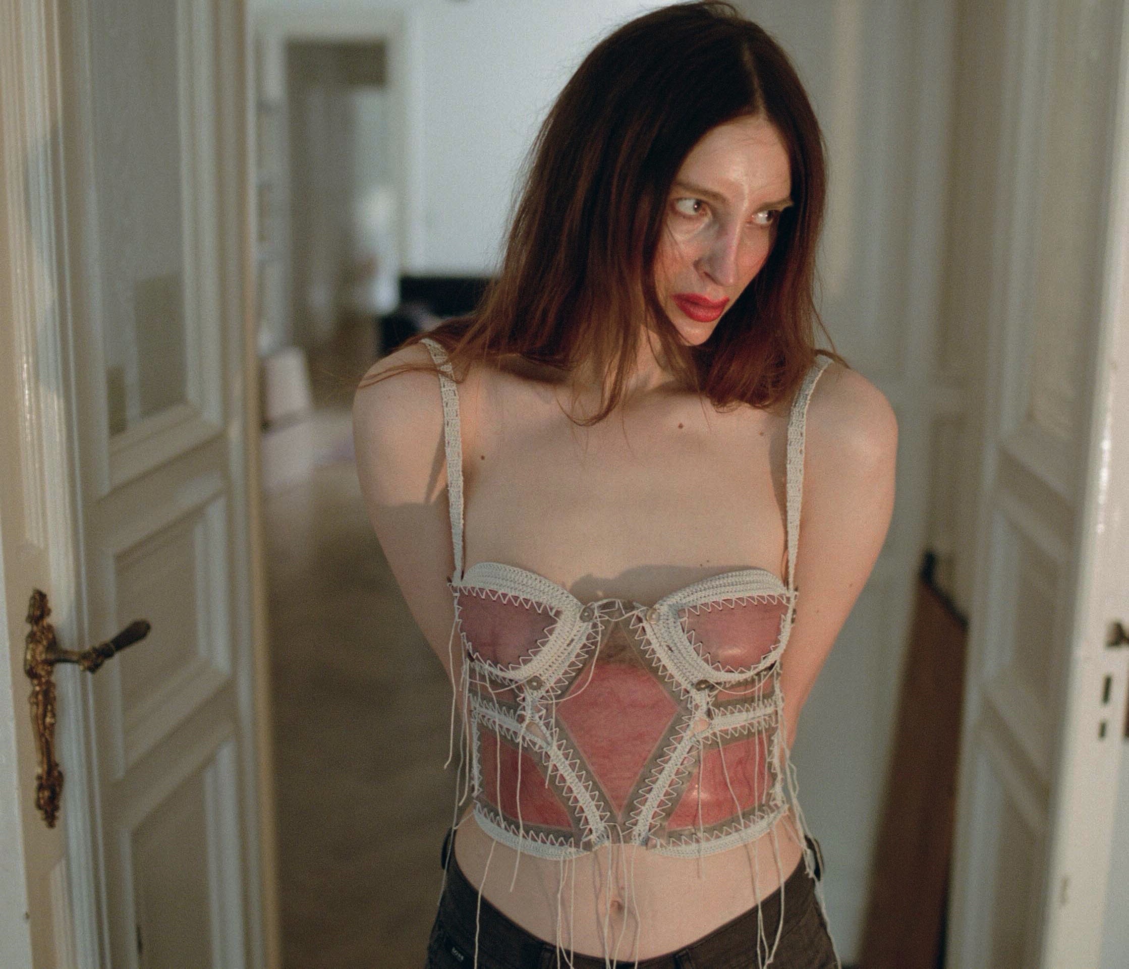 a model in a doorway wearing a pink latex knit corset