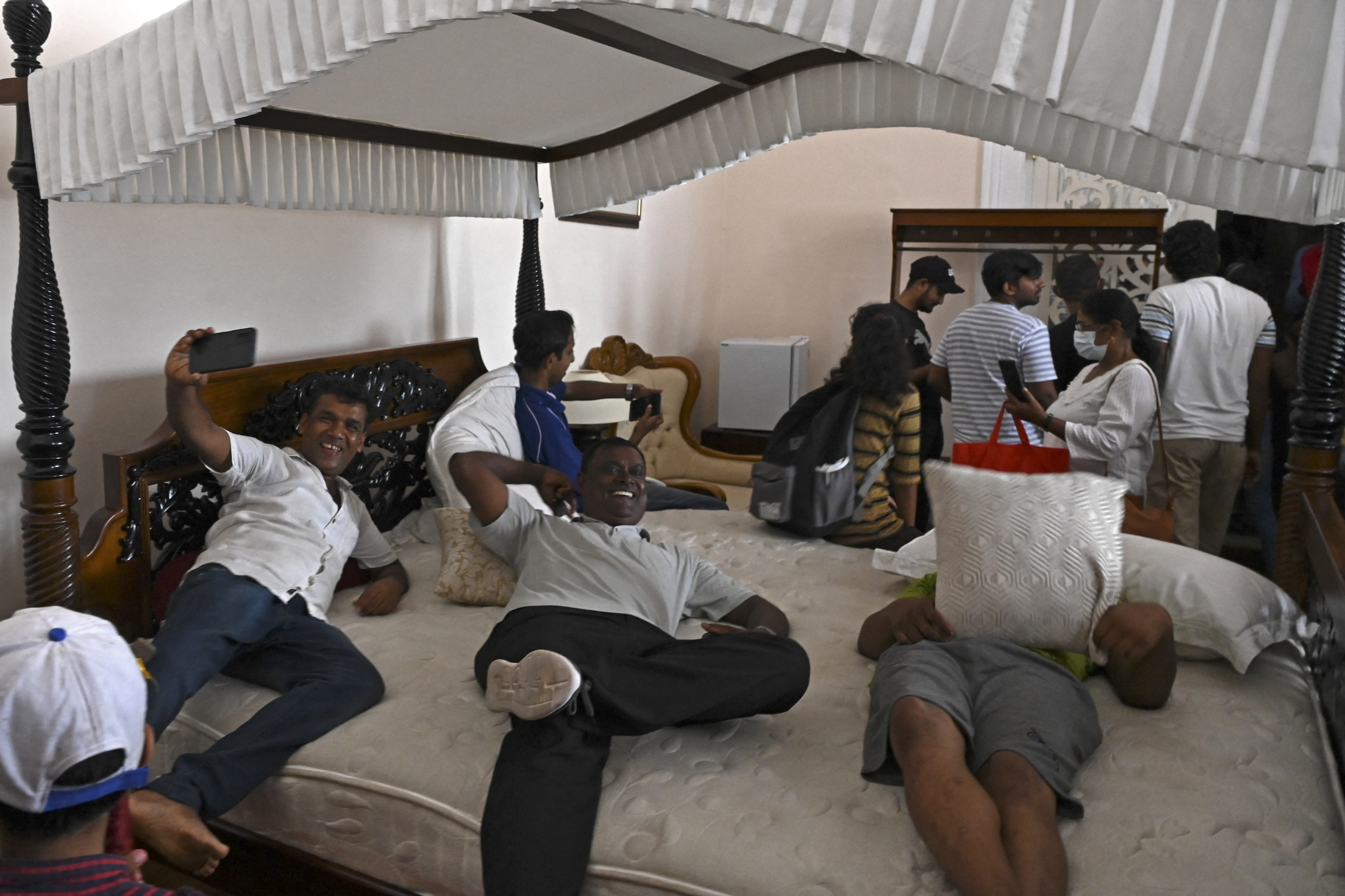 Rakyat Sri Lanka bersantai sambil foto-foto di atas tempat tidur yang ada di Istana Presiden pada 10 Juli 2022. Foto: Arun Sankar / AFP