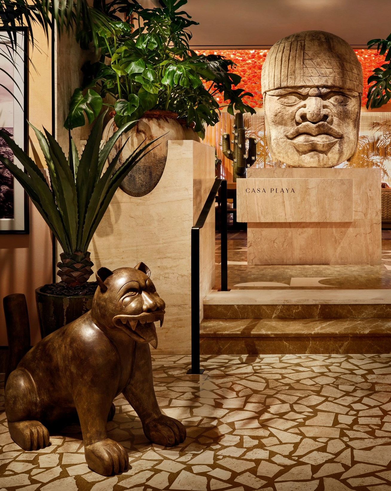The elegant restaurant foyer of Casa Playa decorated in marble and stone, with sculptures and tropical plants.