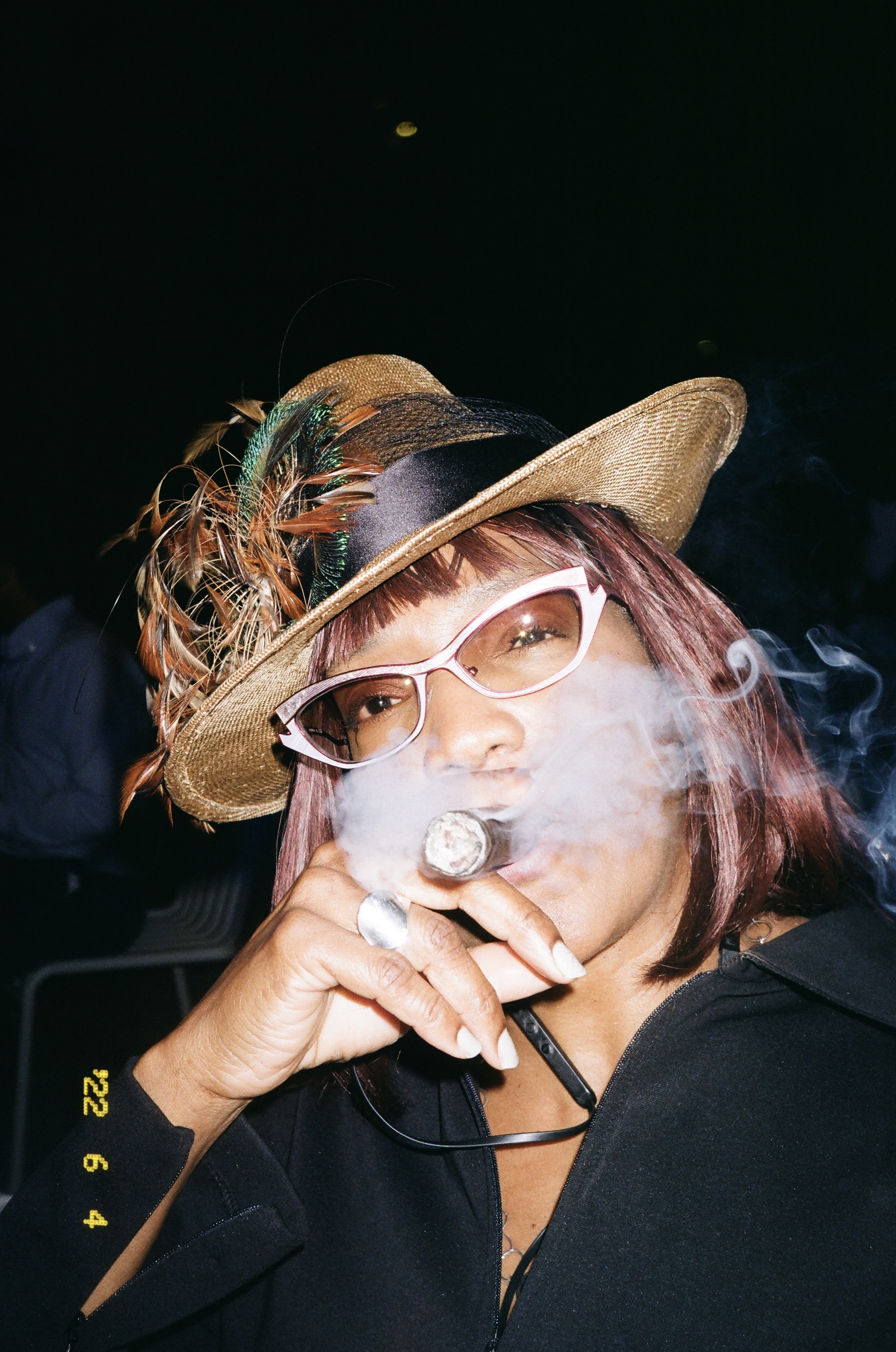     A woman in a straw hat and sunglasses smoking a cigar.
