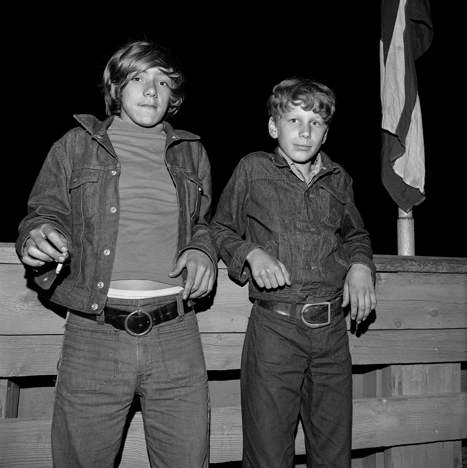 Dua remaja laki-laki bersandar di pagar kayu