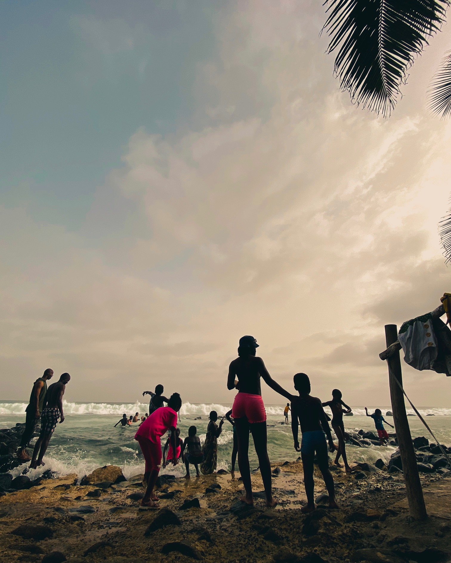 People standing on the beach, entering the ocean as the waves crash in