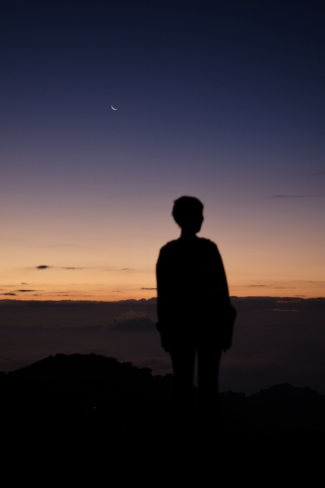 person standing on a mountain overlooking the sunrise
