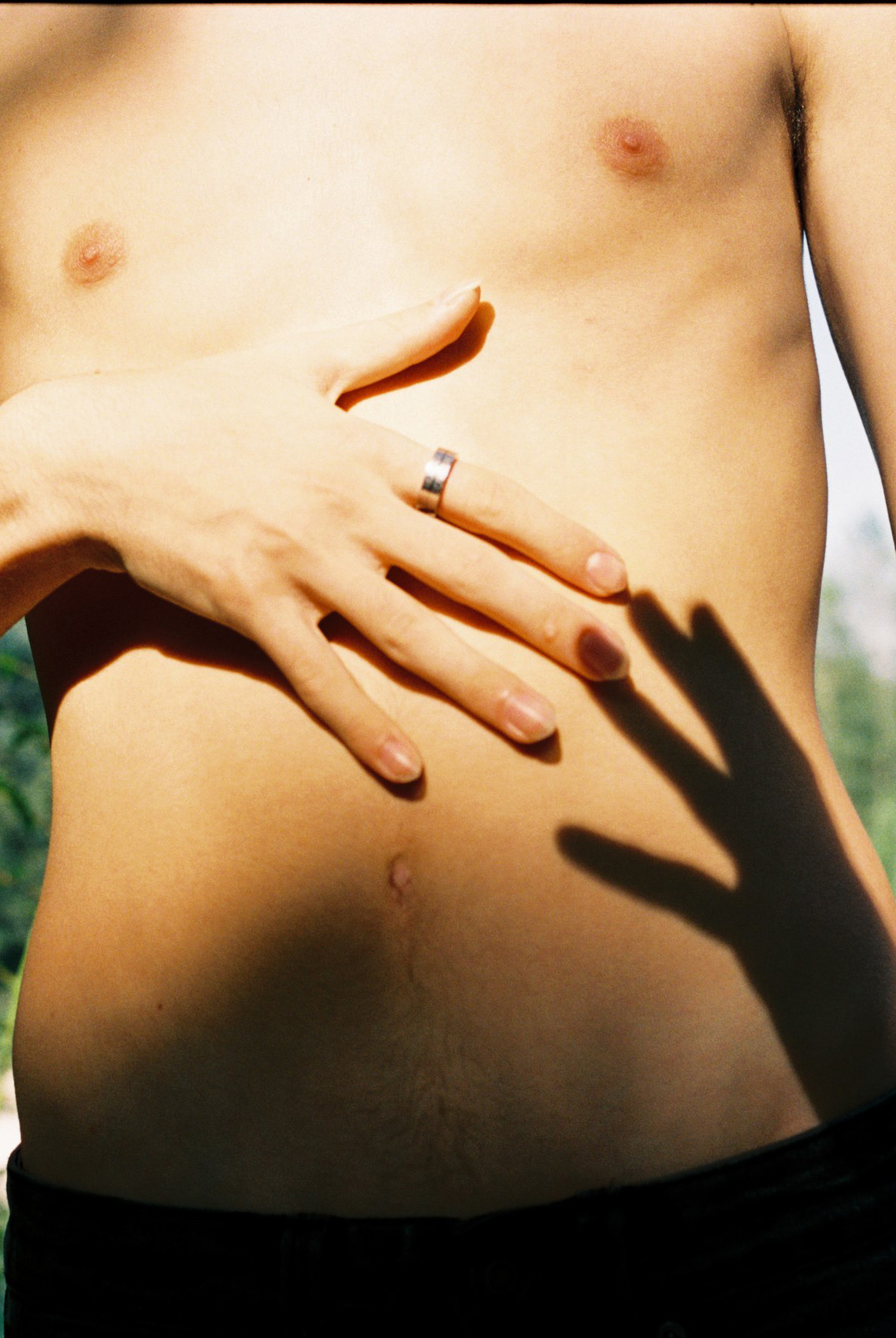the shadow of a hand cast on a bare chested persons body
