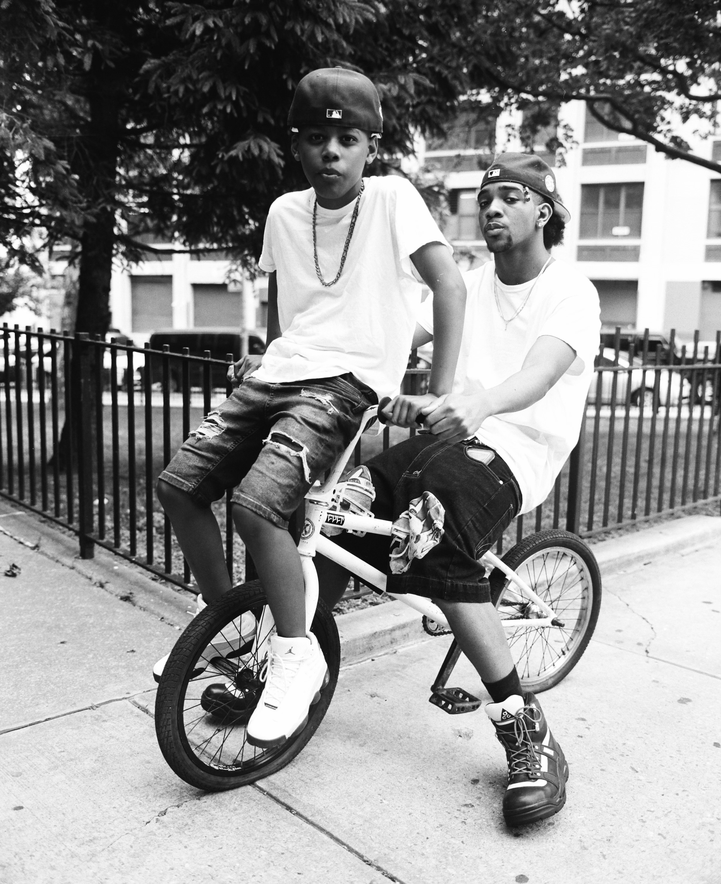 Two boys sitting on a bike, one on the seat the other on the handle bars