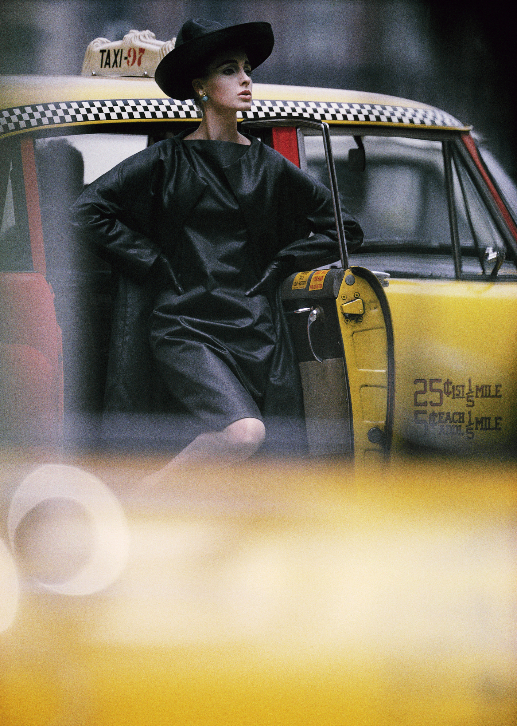 Photo of a woman in a leather dress and hat stepping out of a yellow cab
