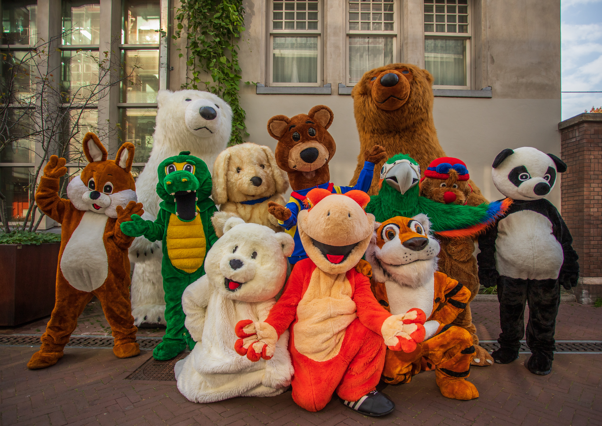 group picture of a bunch of mascots. There's a squirrel, white and brown bears, crocodile, tiger, parrot, panda and a dog