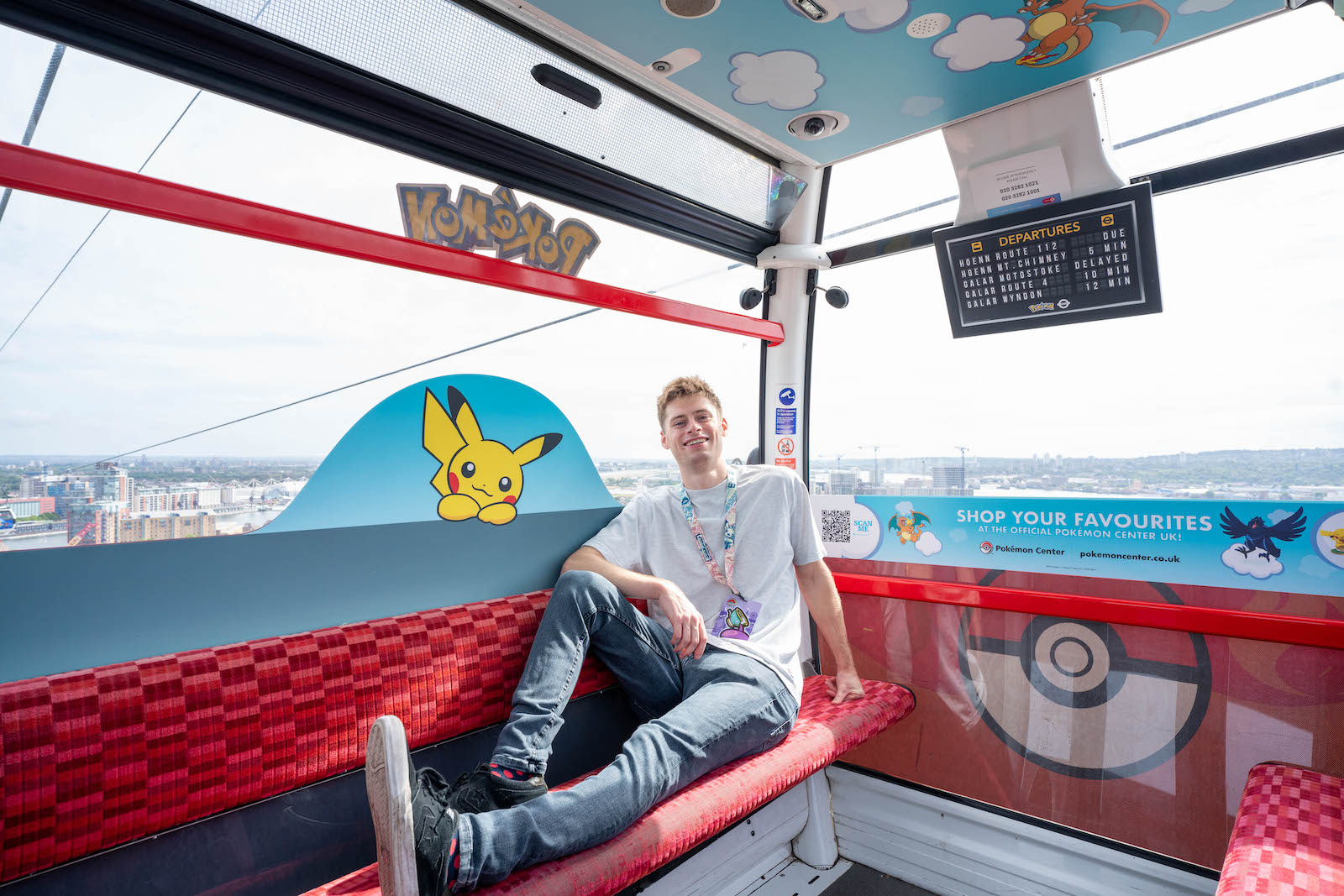 Lelaki berkaus putih naik kereta gantung yang dekorasinya penuh gambar Pokemon dan Pikachu