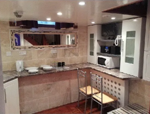 The kitchen with a hole cut in the ceiling of a double mezzanine studio to rent in
