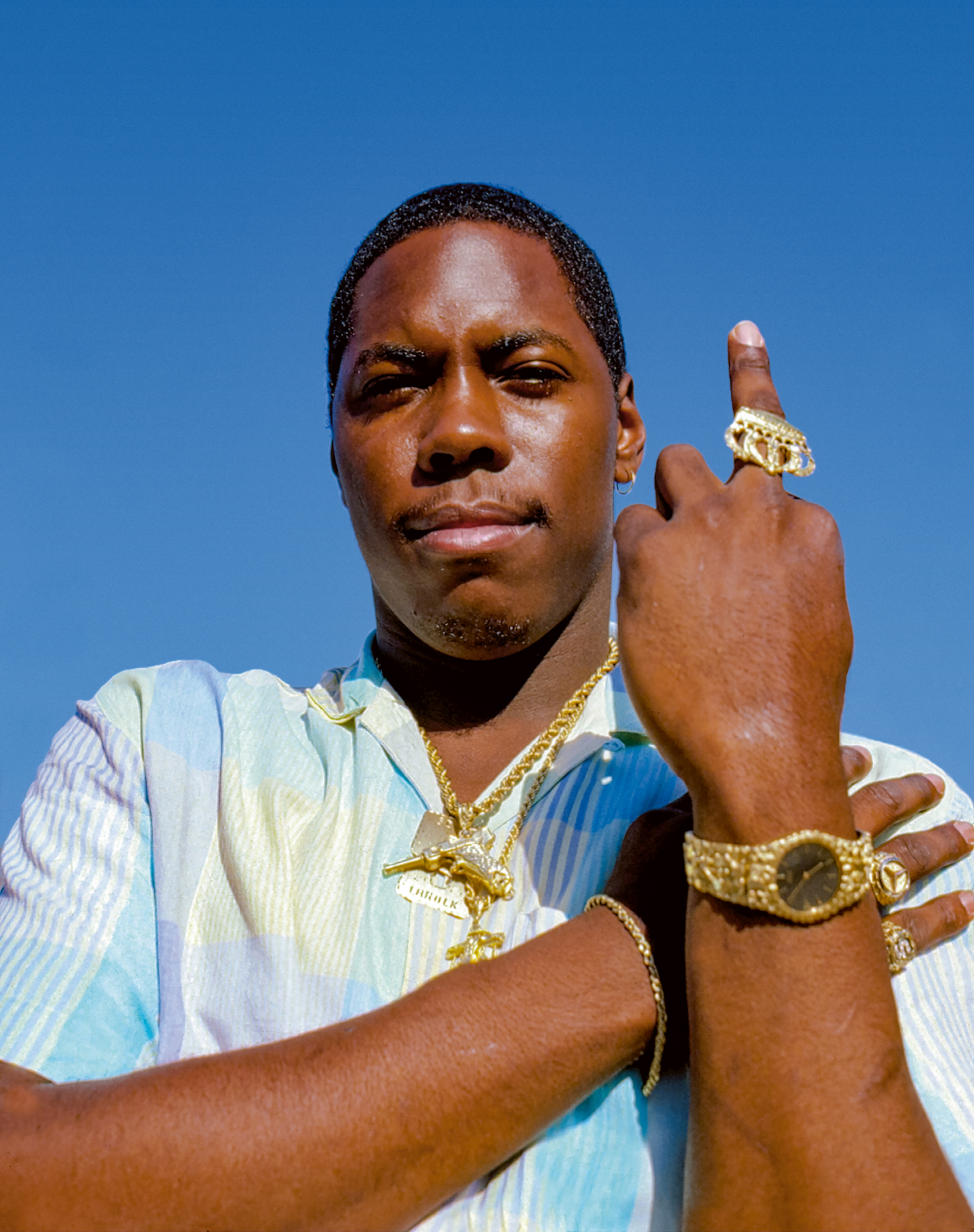 Scott La Rock wearing gold crown ring, gold nugget watch, nameplate necklace, Mercedes-Benz logo ring