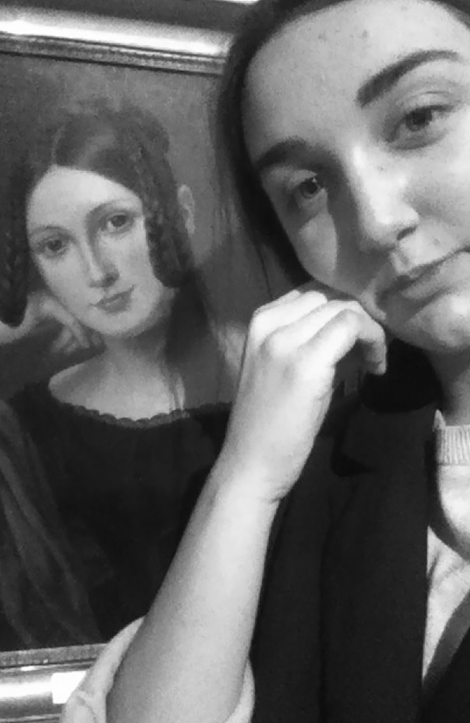 Perempuan selfie di depan lukisan perempuan berpangku tangan. Fitur wajah perempuan dalam lukisan dan foto sangat mirip.