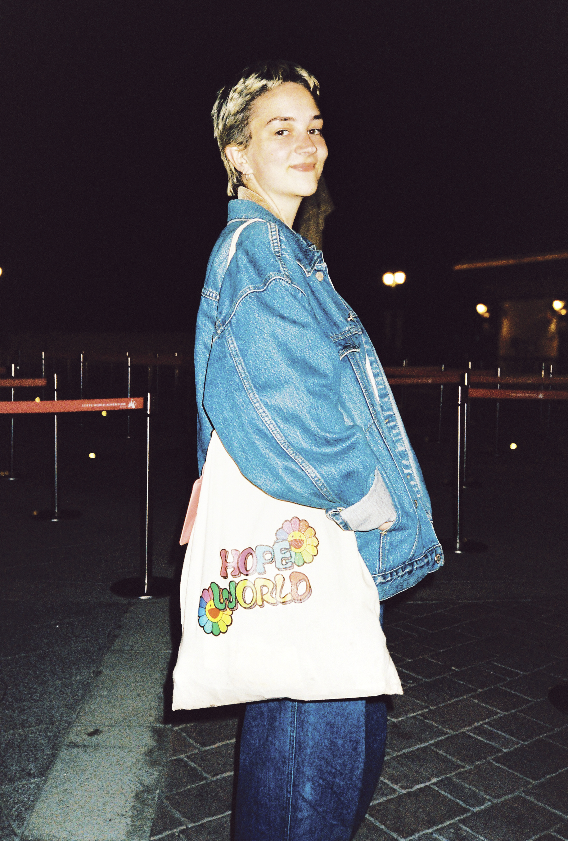 a fan with short bleached hair dressed in all denim looks over their shoulder