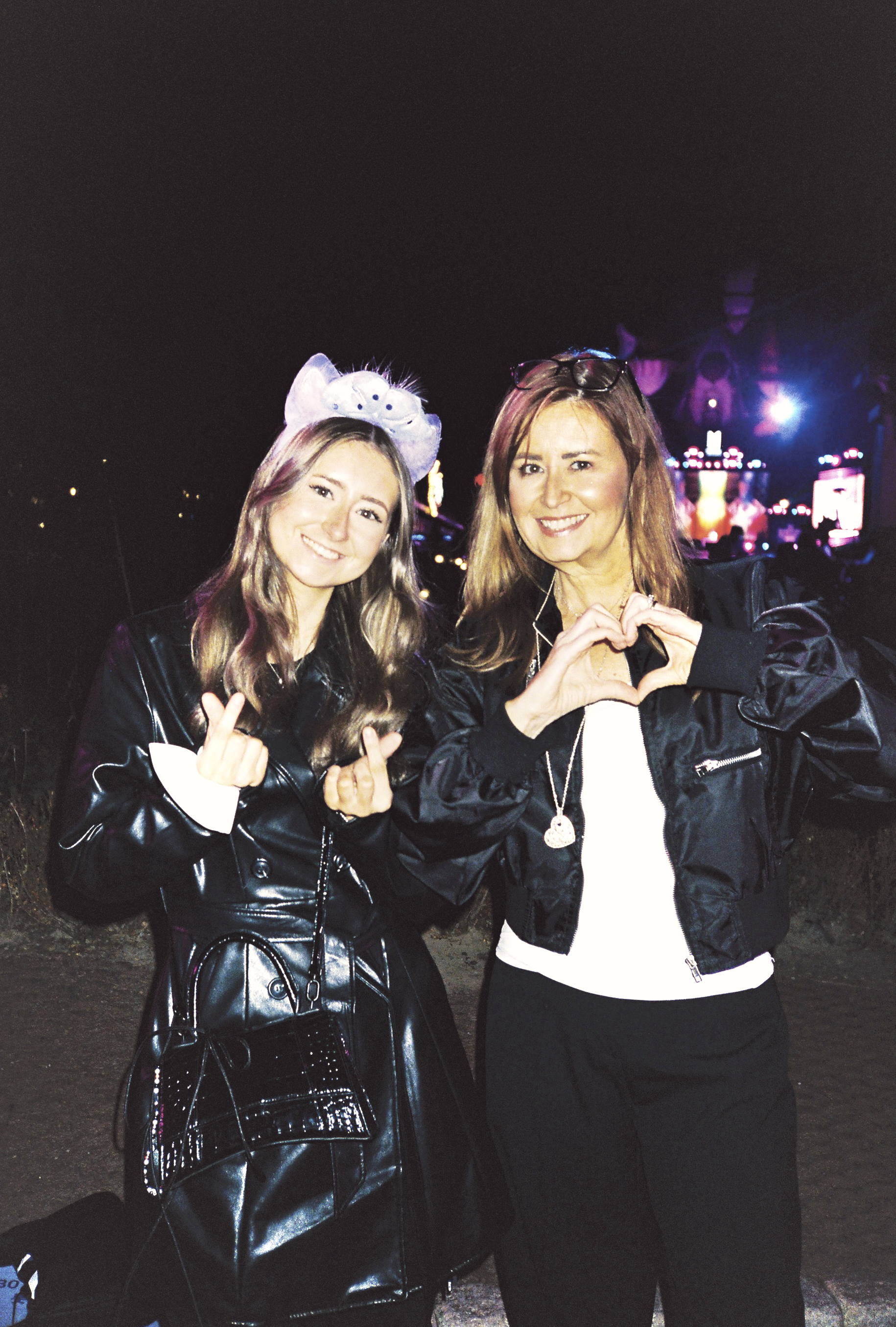 two women in shiny black jackets pose for a straight up