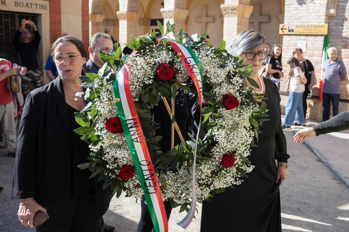 Rangkaian bunga berwarna bendera Italia yang dihiasi selempang “100 Tahun”.