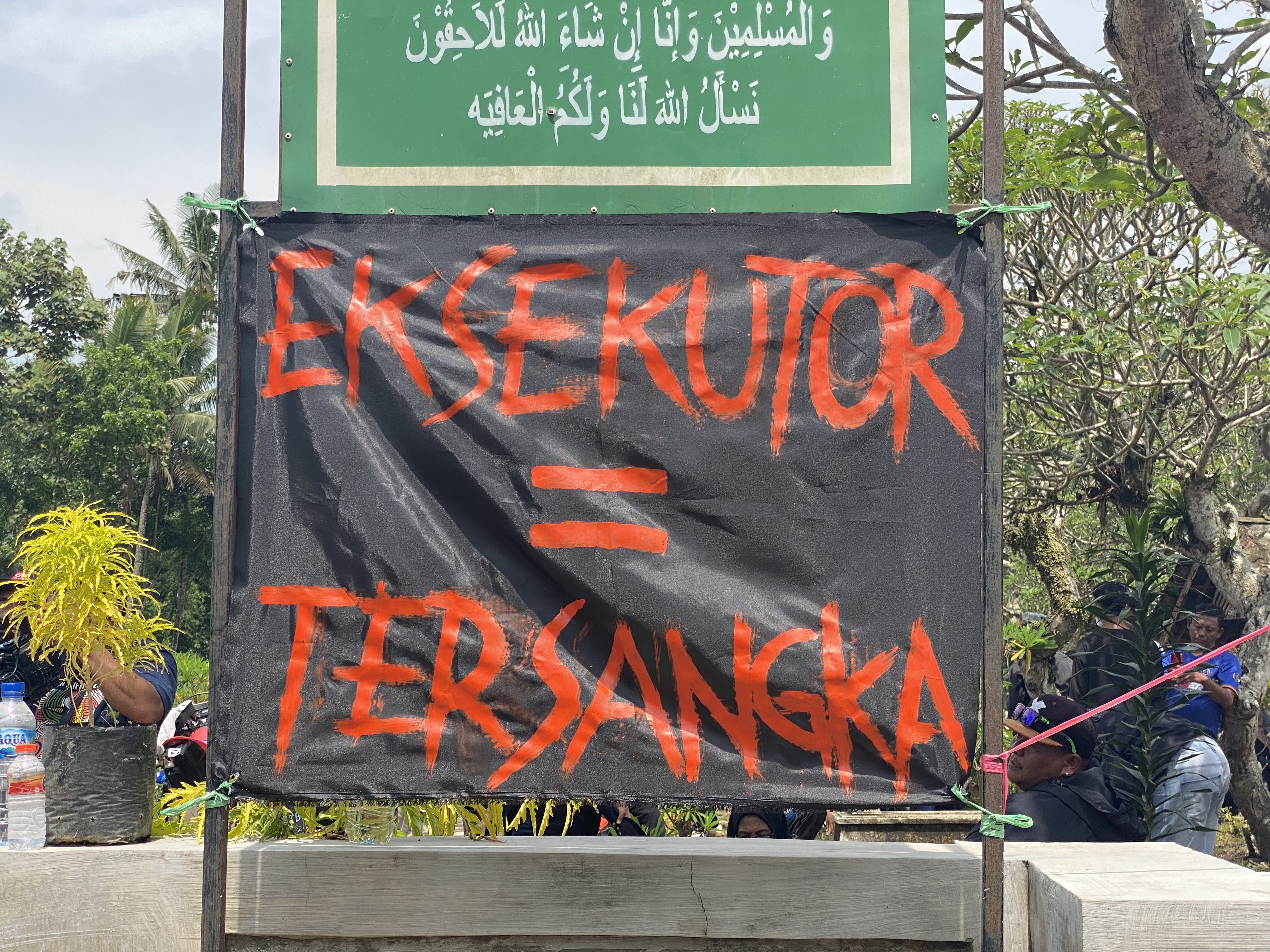 Poster bertuliskan “Executioner = Tersangka” terpasang di area pemakaman.