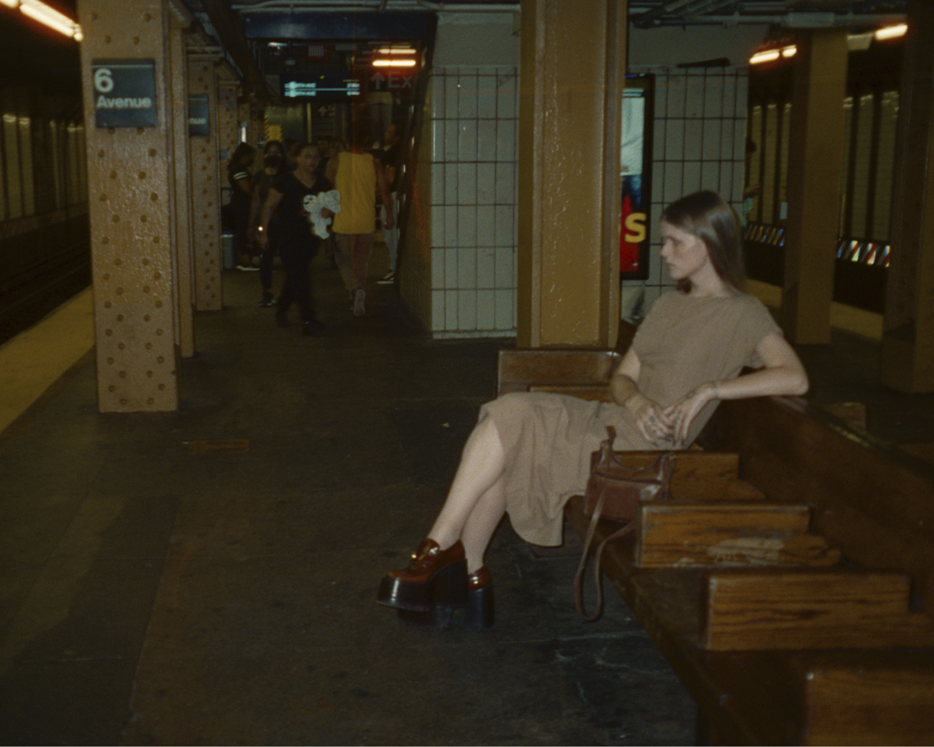 Ethel Cain sitting on a wooden bench in a subway station in a photograph by Silken Weinberg featured in i-D’s The Royalty Issue, no. 370, Winter 2022
