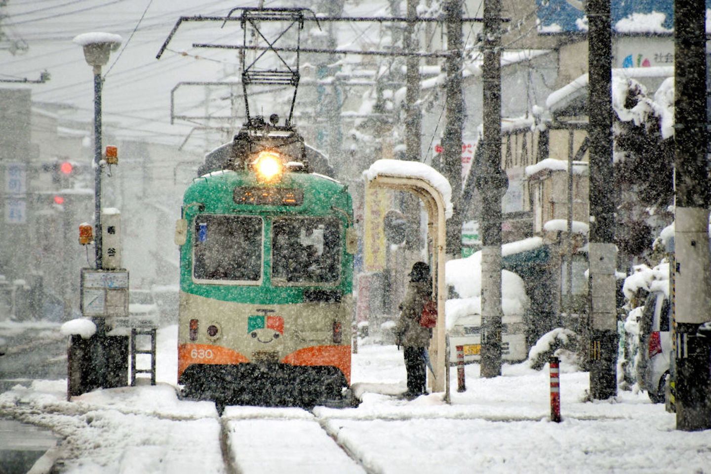 Trem membelah jalanan bersalju di Kochi, Jepang, pada 23 Desember 2022. Foto: The Asahi Shimbun via Getty Images