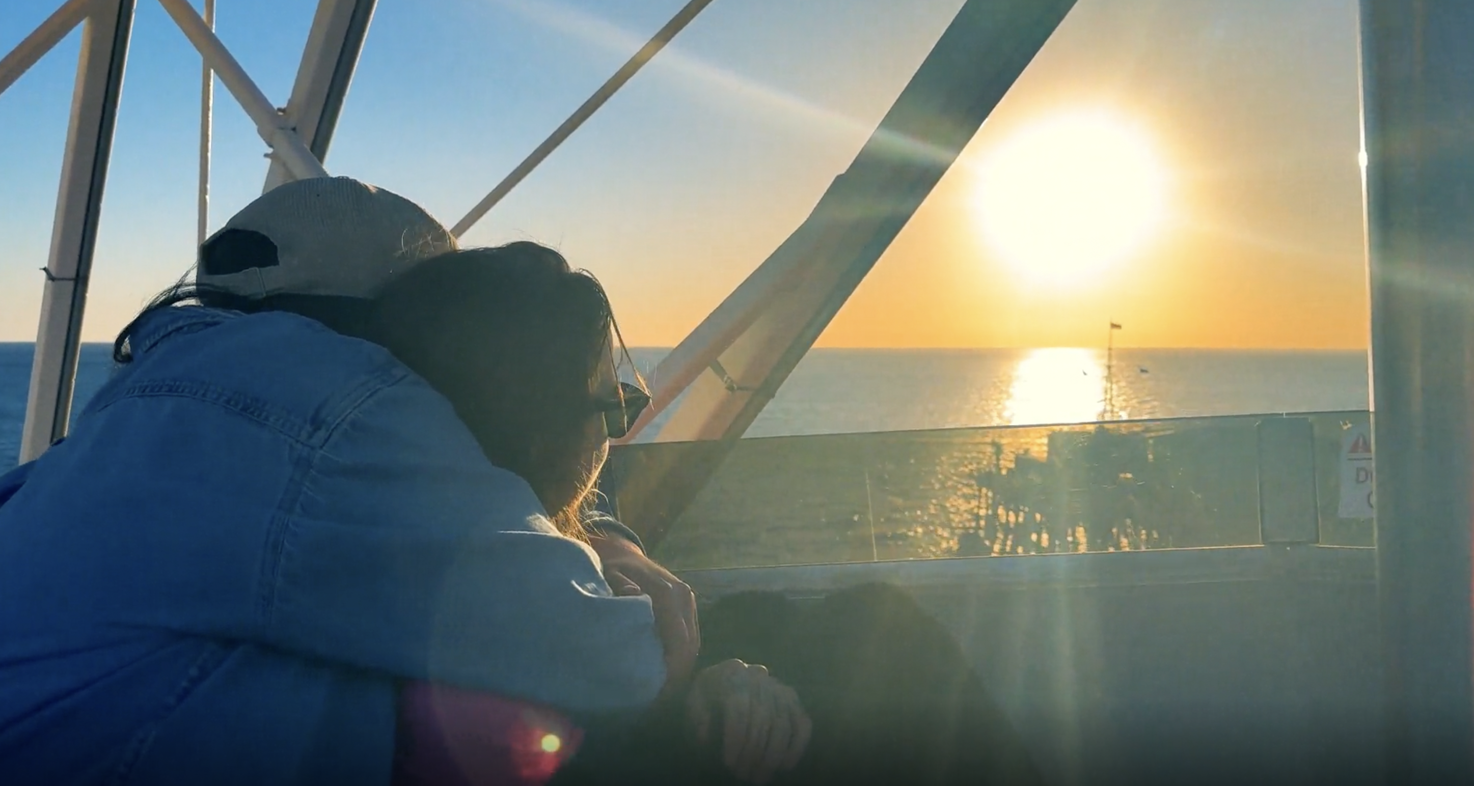 julien baker and lucy dacus hug at sunset on a pier