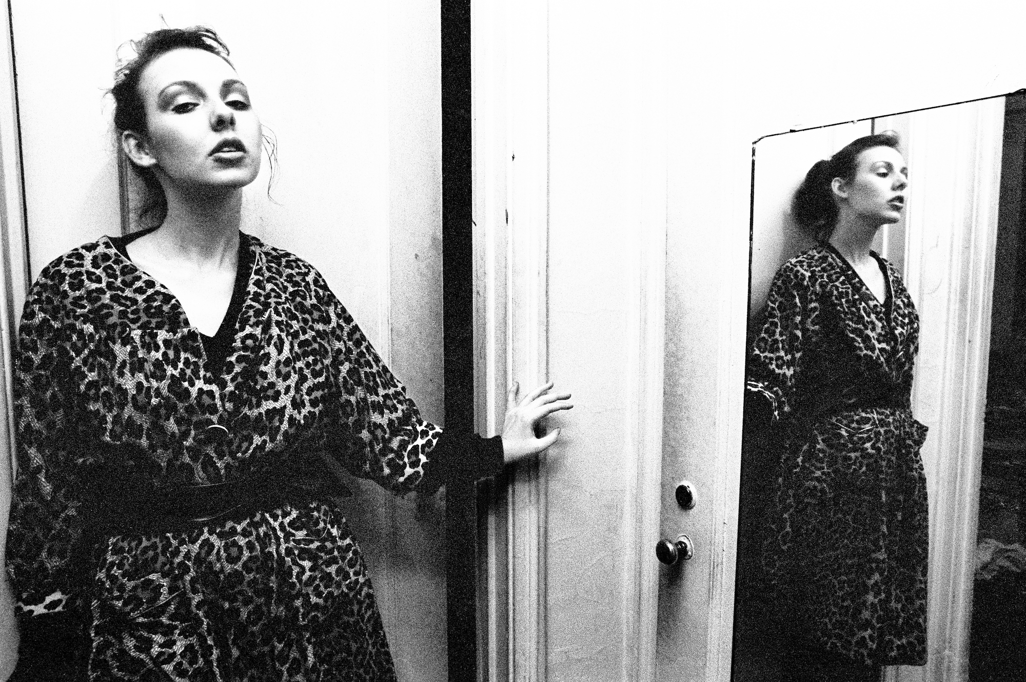 a woman posing in a leopard robe in front of the mirror