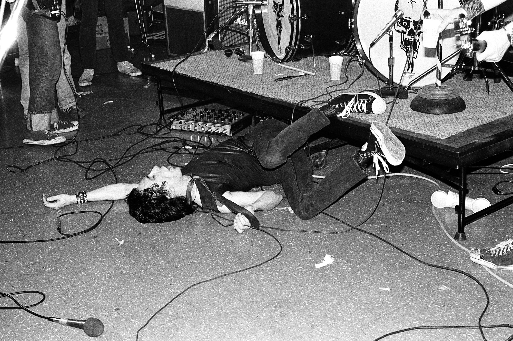 a man in a tie and converse falling off stage