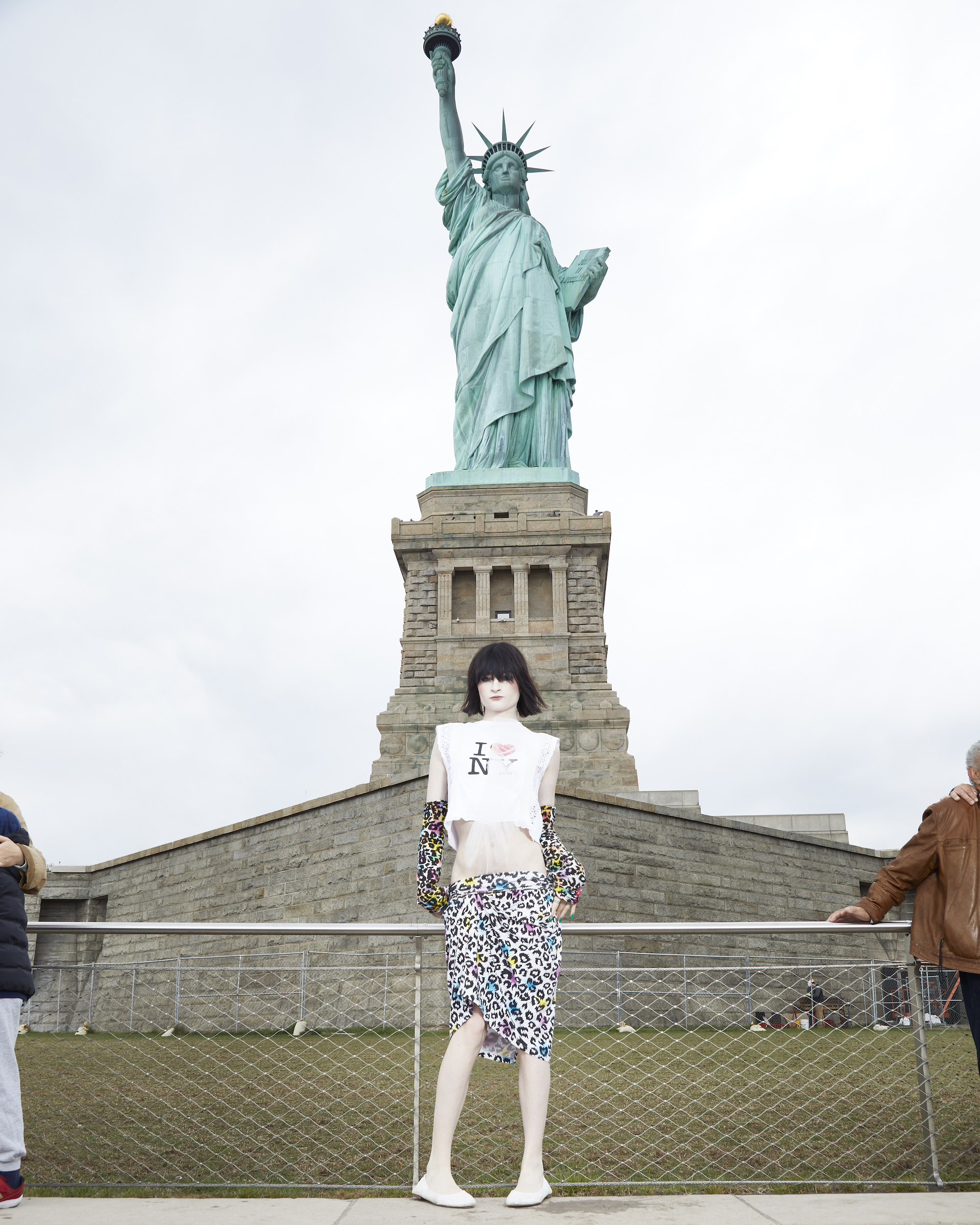 ren g wearing an I love new york t-shirt posing in front of the statue of liberty