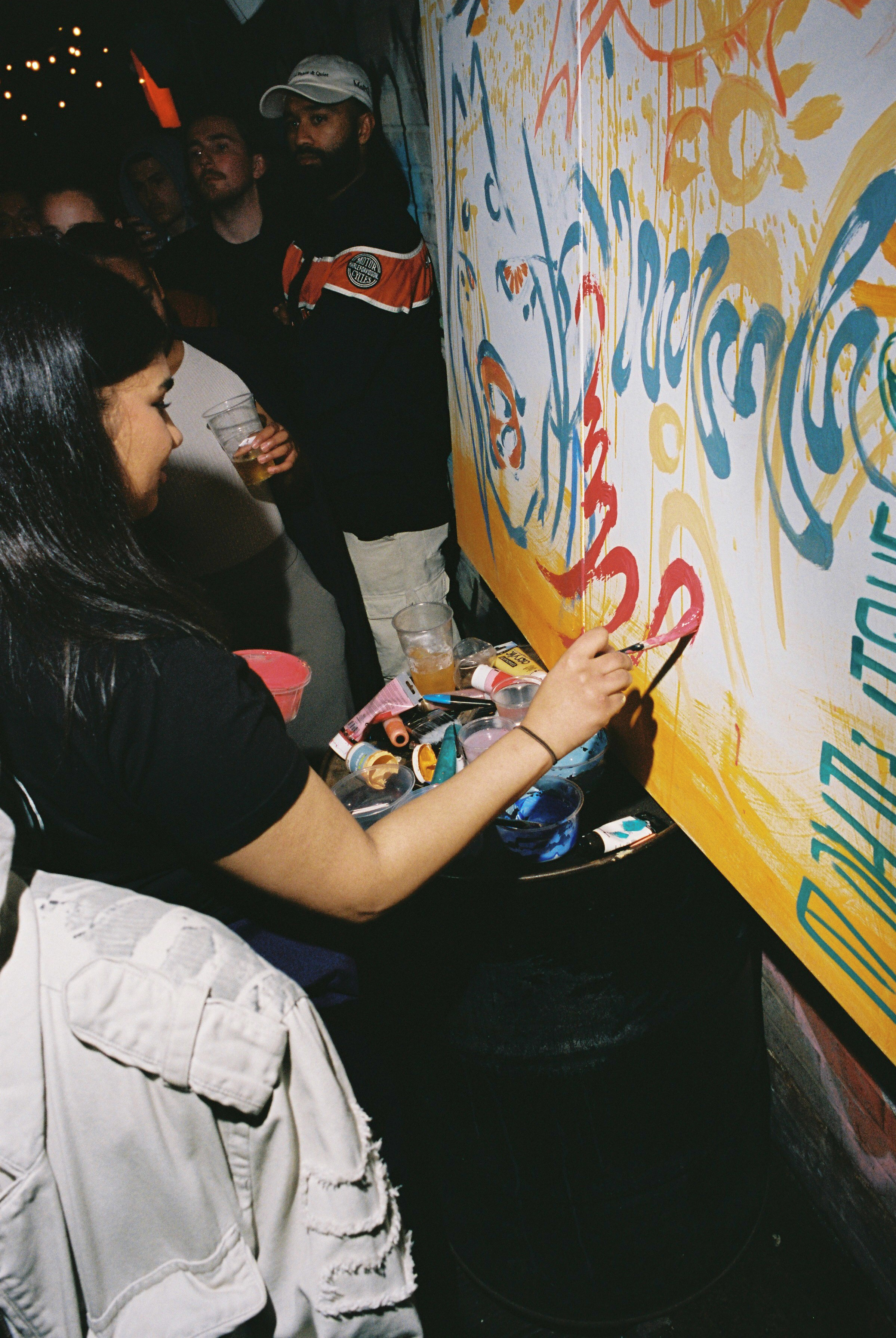 a girl painting on a wall at da collective event in london
