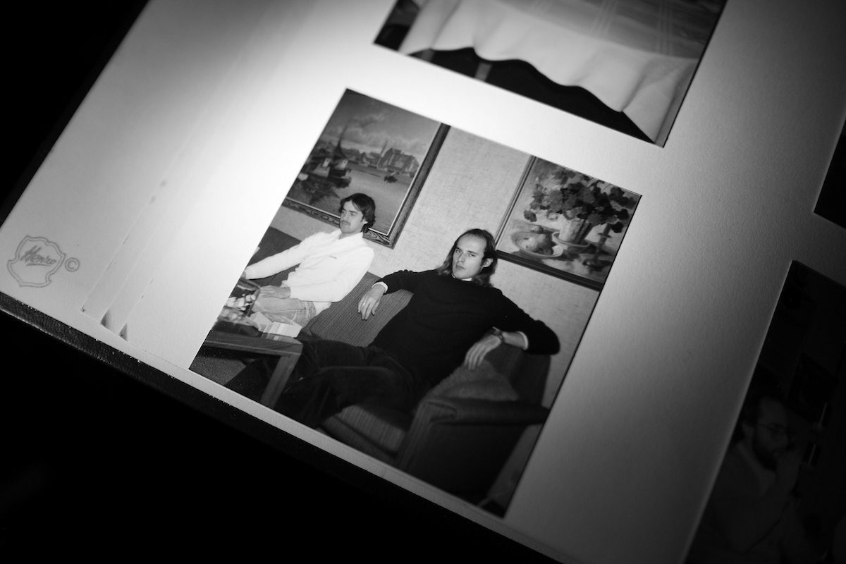 Mikkel Hørlyck, Jørgen, a Mystery – photo album with picture of two men sitting on a couch in front of a coffee table with two large paintings behind them