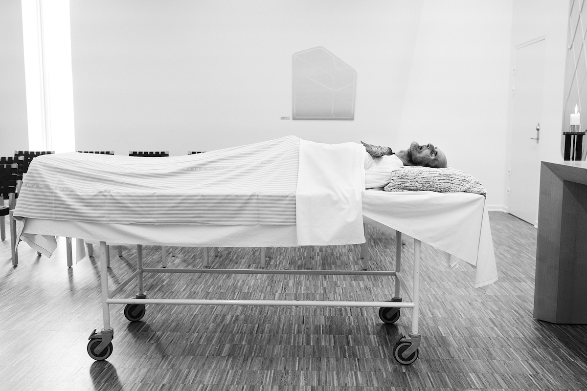 Ein toter Mann liegt aufgebahrt in einem Krankenhausbett in einer Kapelle