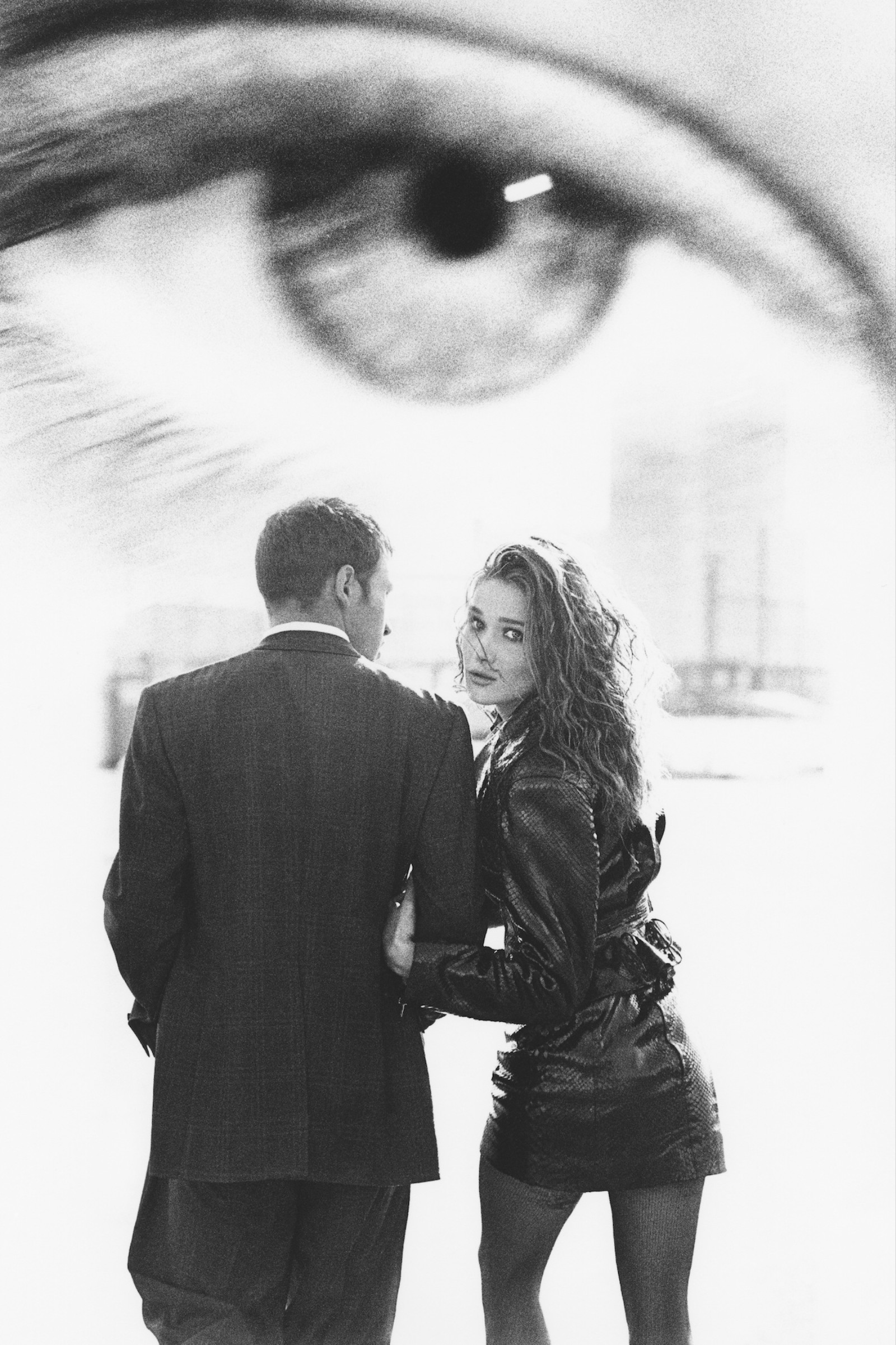 black-and-white image of carla bruni holding onto a man's arm with an eye in the distance