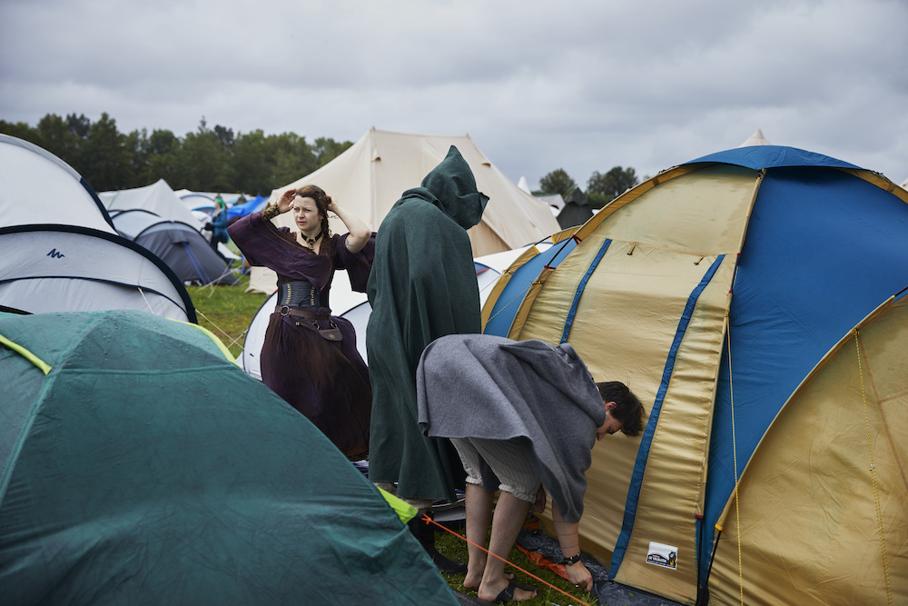 Menschen in Mittelalteroutfits bei schlechtem Wetter auf einem Zeltplatz