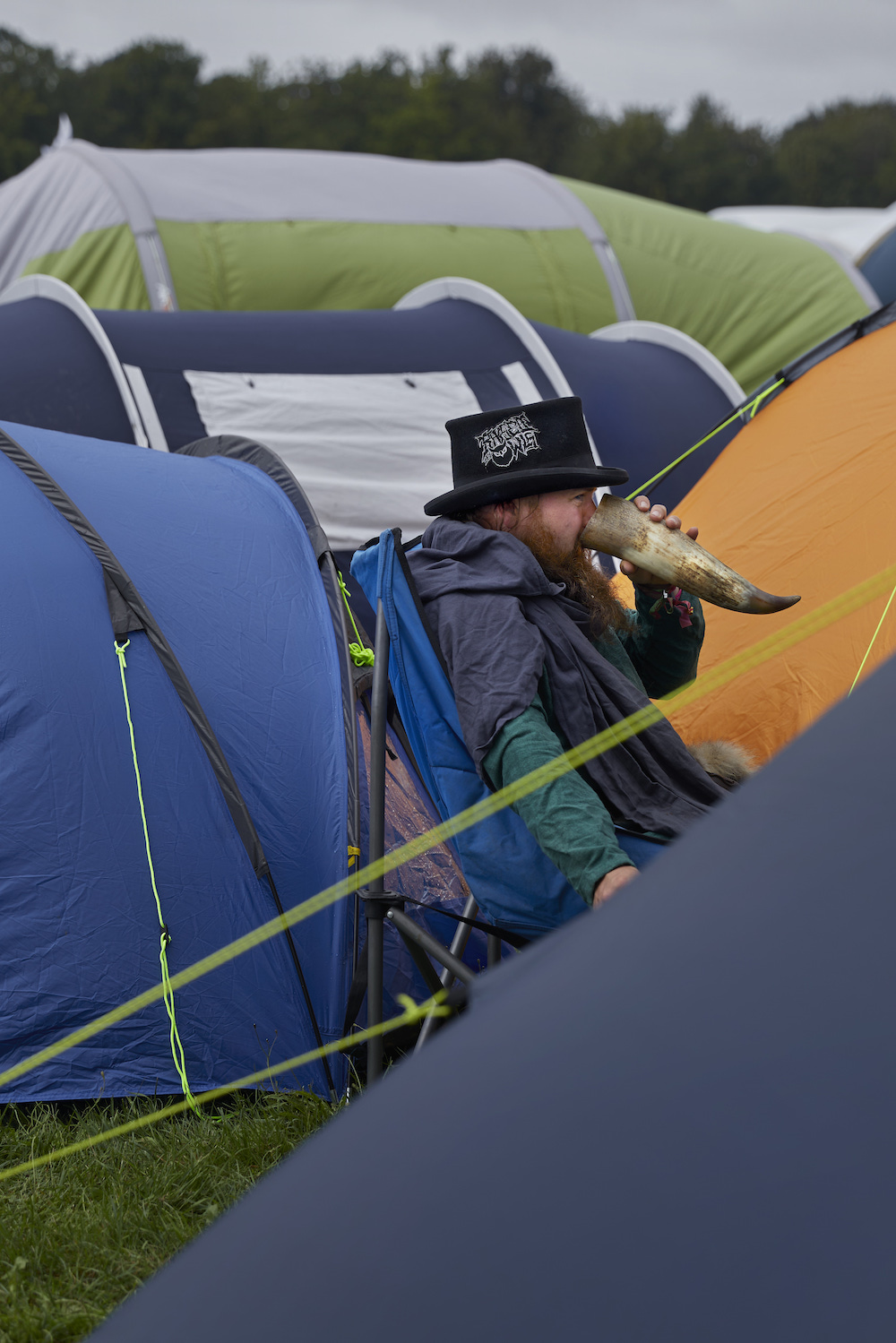 Ein Mann sitzt zwischen Zelten und trinkt aus einem großen Horn